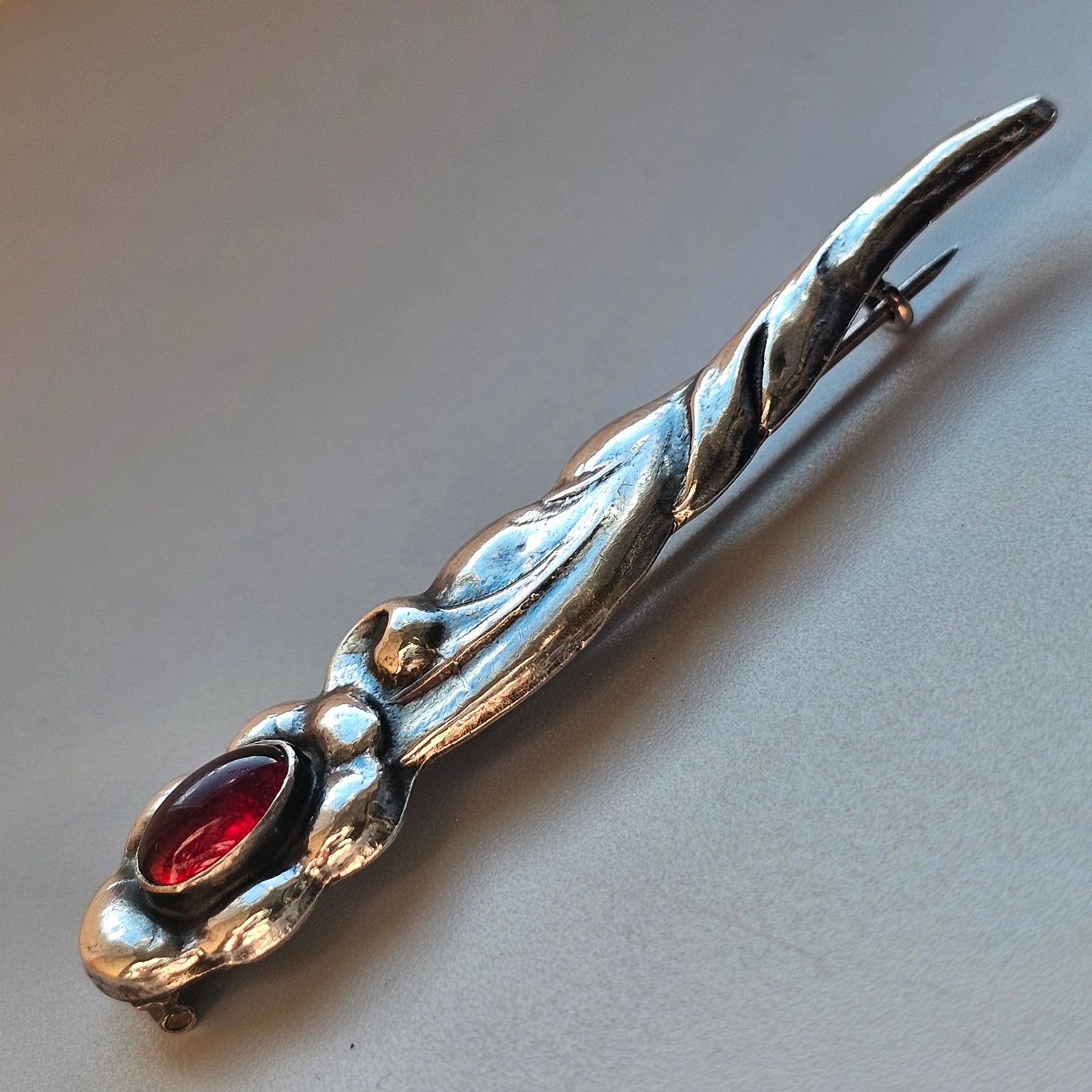 Ornate silver letter opener with a red gemstone inlay.