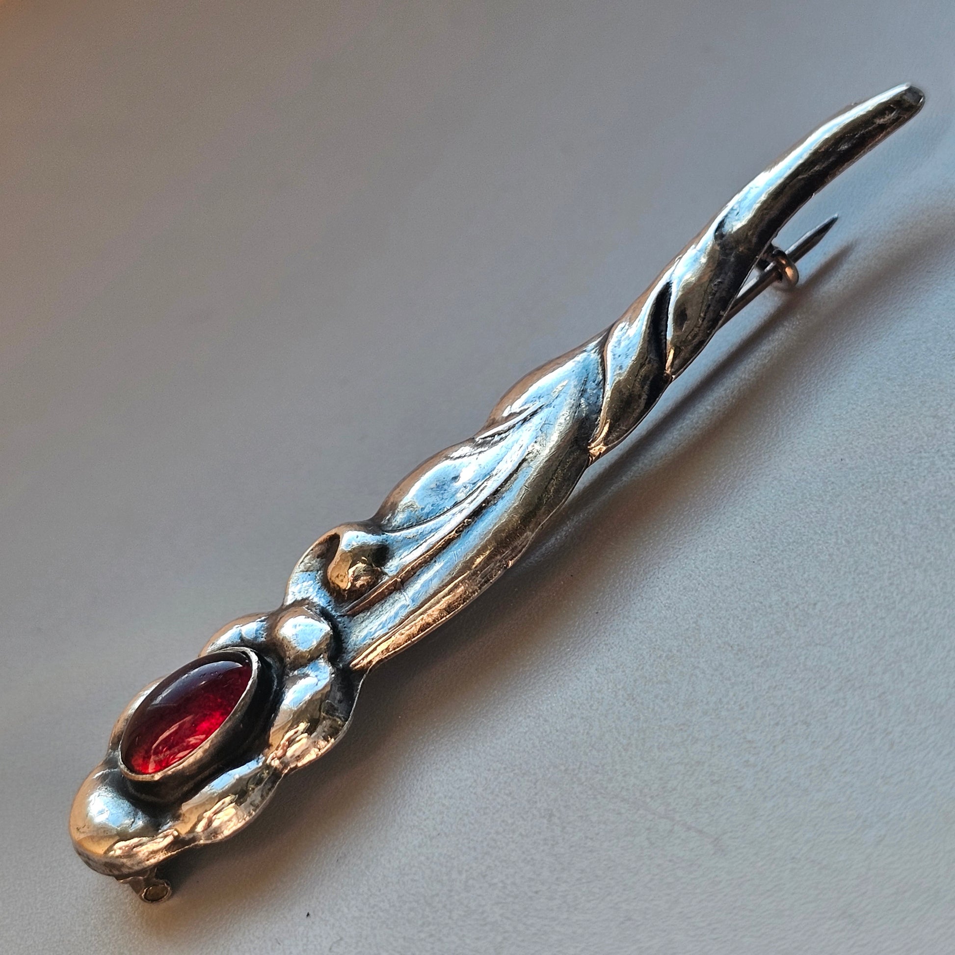 Ornate silver letter opener with a red gemstone inlay.