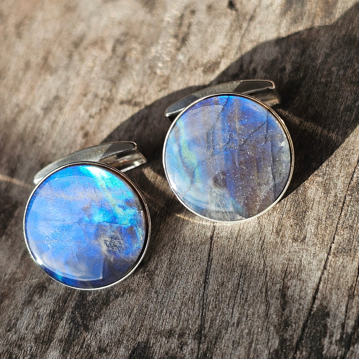 Pair of round cufflinks with iridescent blue gemstones or crystals.