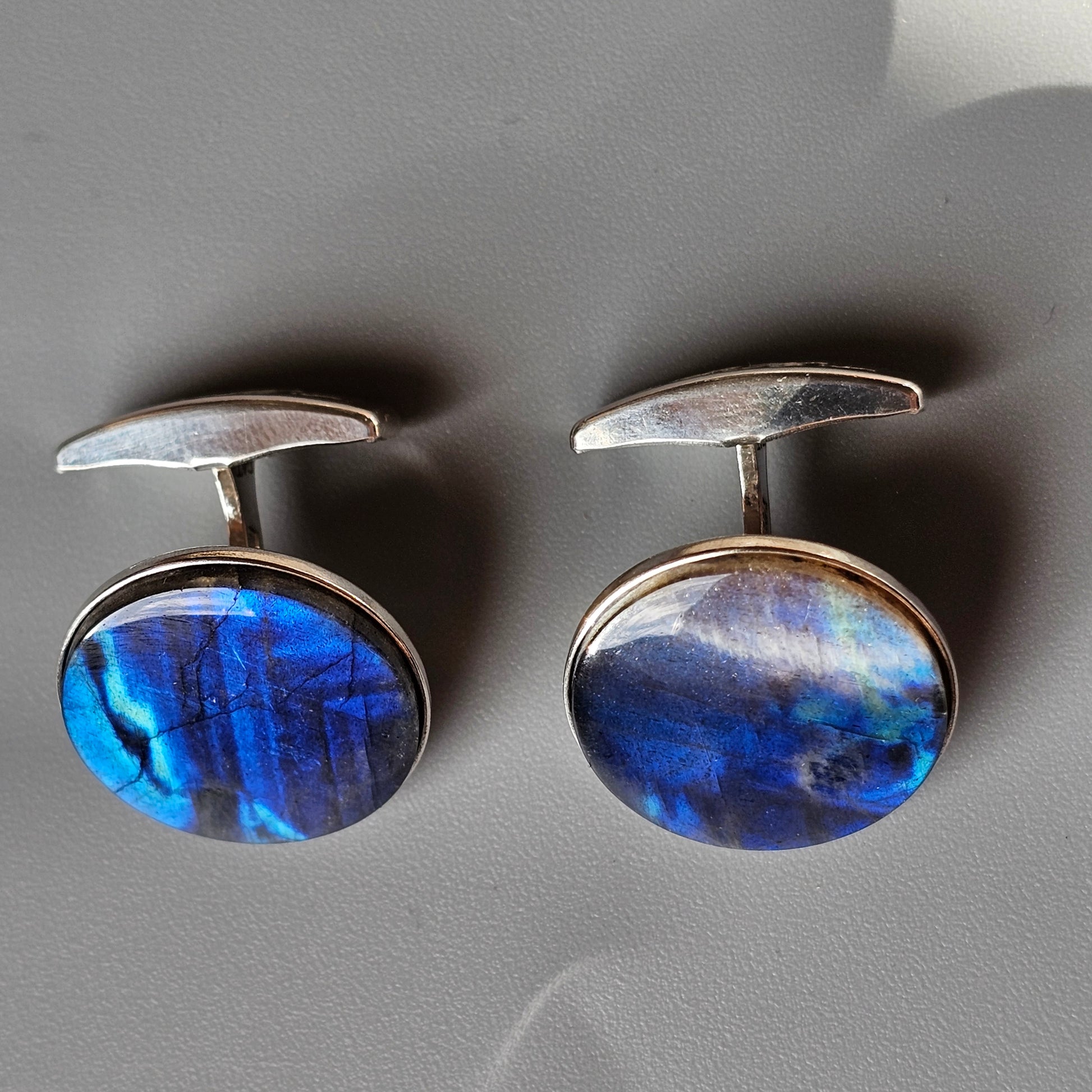 Pair of oval cufflinks with iridescent blue gemstones.