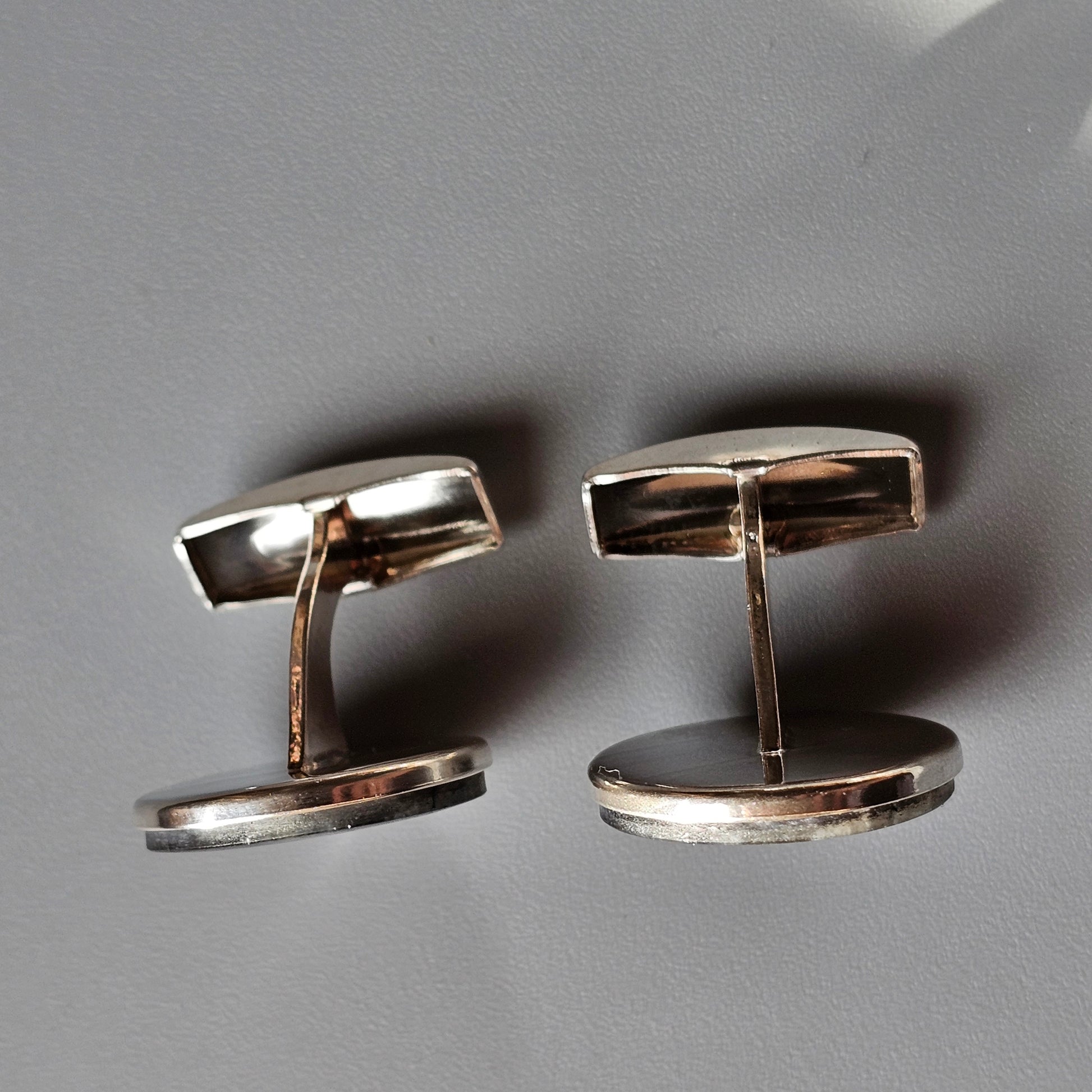 Pair of silver-toned metal cufflinks with rectangular tops and circular bases.