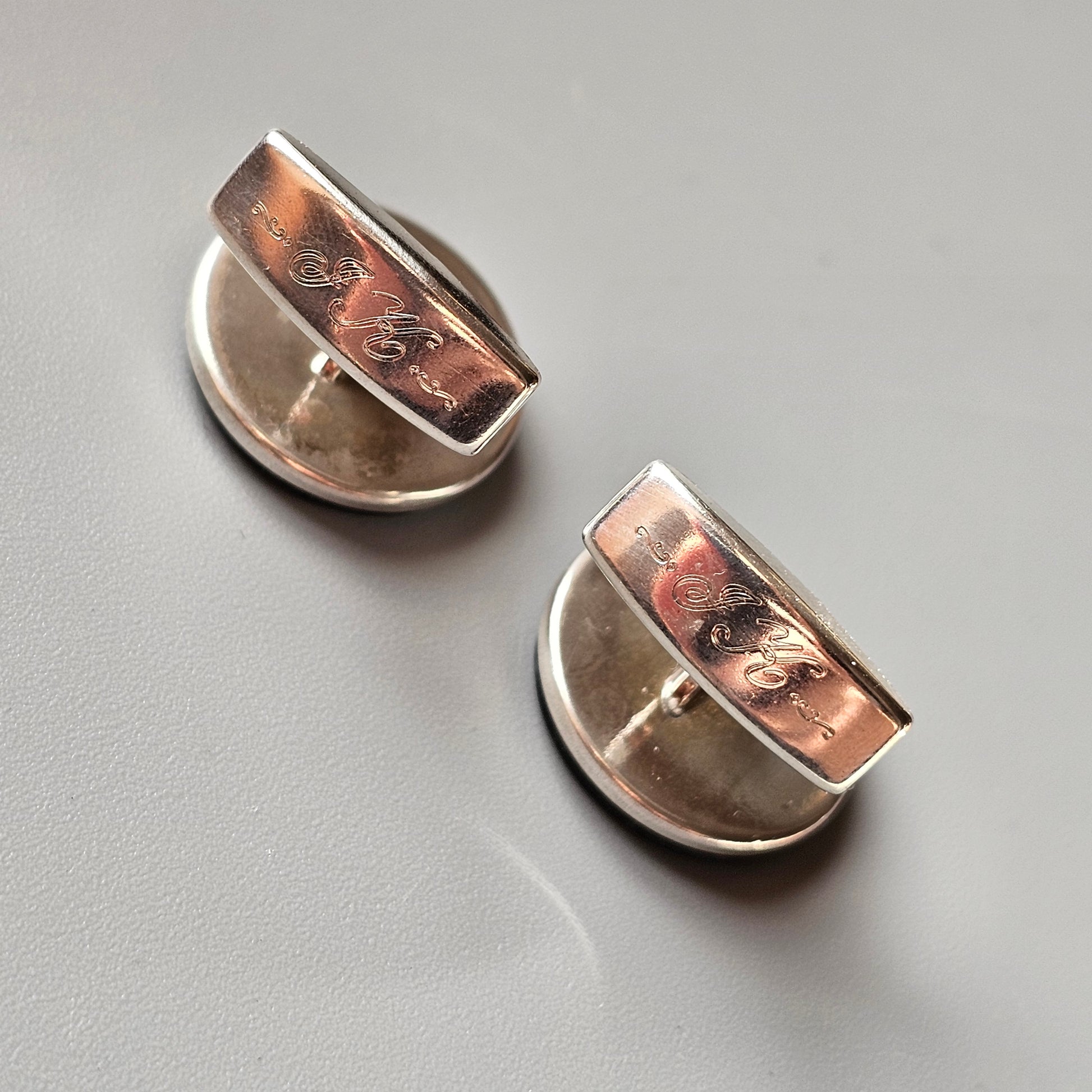 Pair of semicircular earrings with copper-colored accents on silver-toned metal.