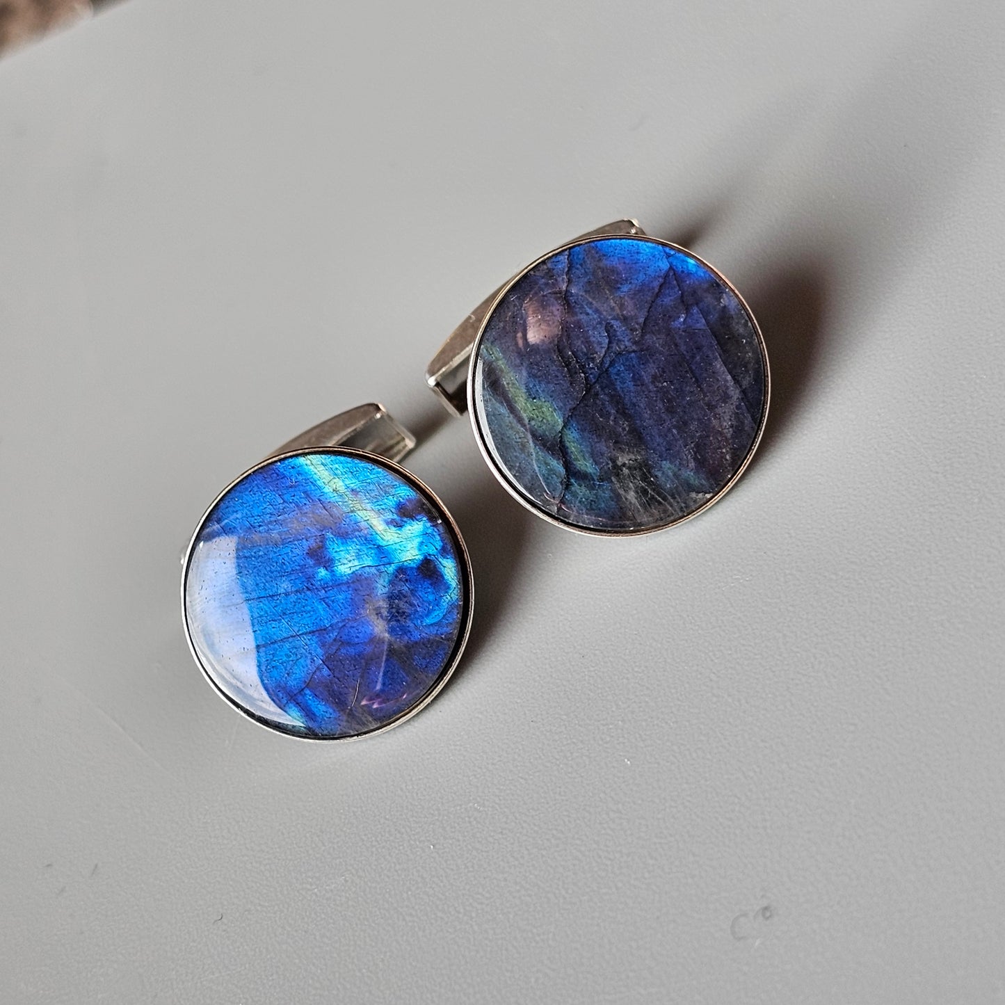 Pair of round cufflinks with iridescent blue and purple gemstones or glass inlays.