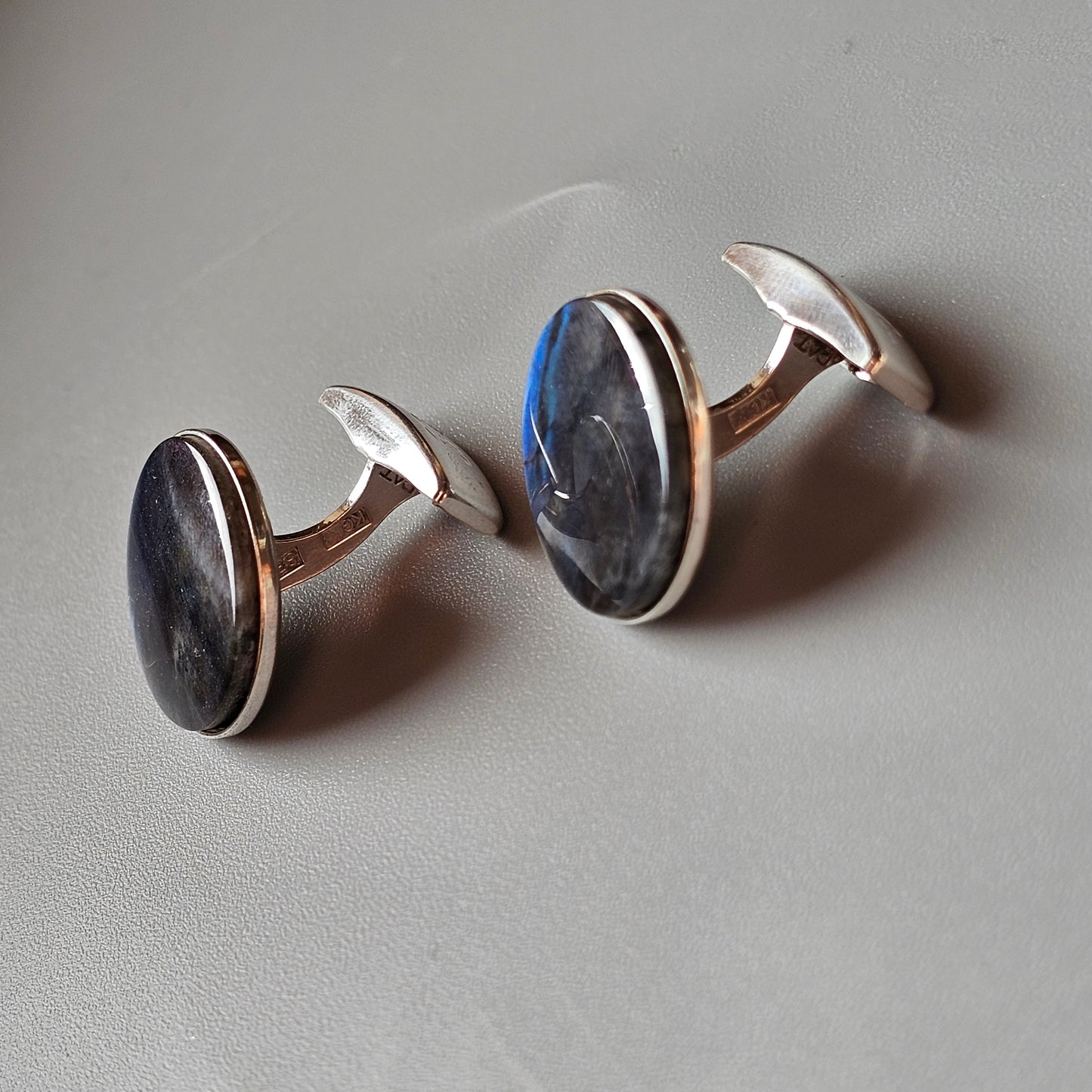 Pair of oval cufflinks with dark stones set in silver or white metal.