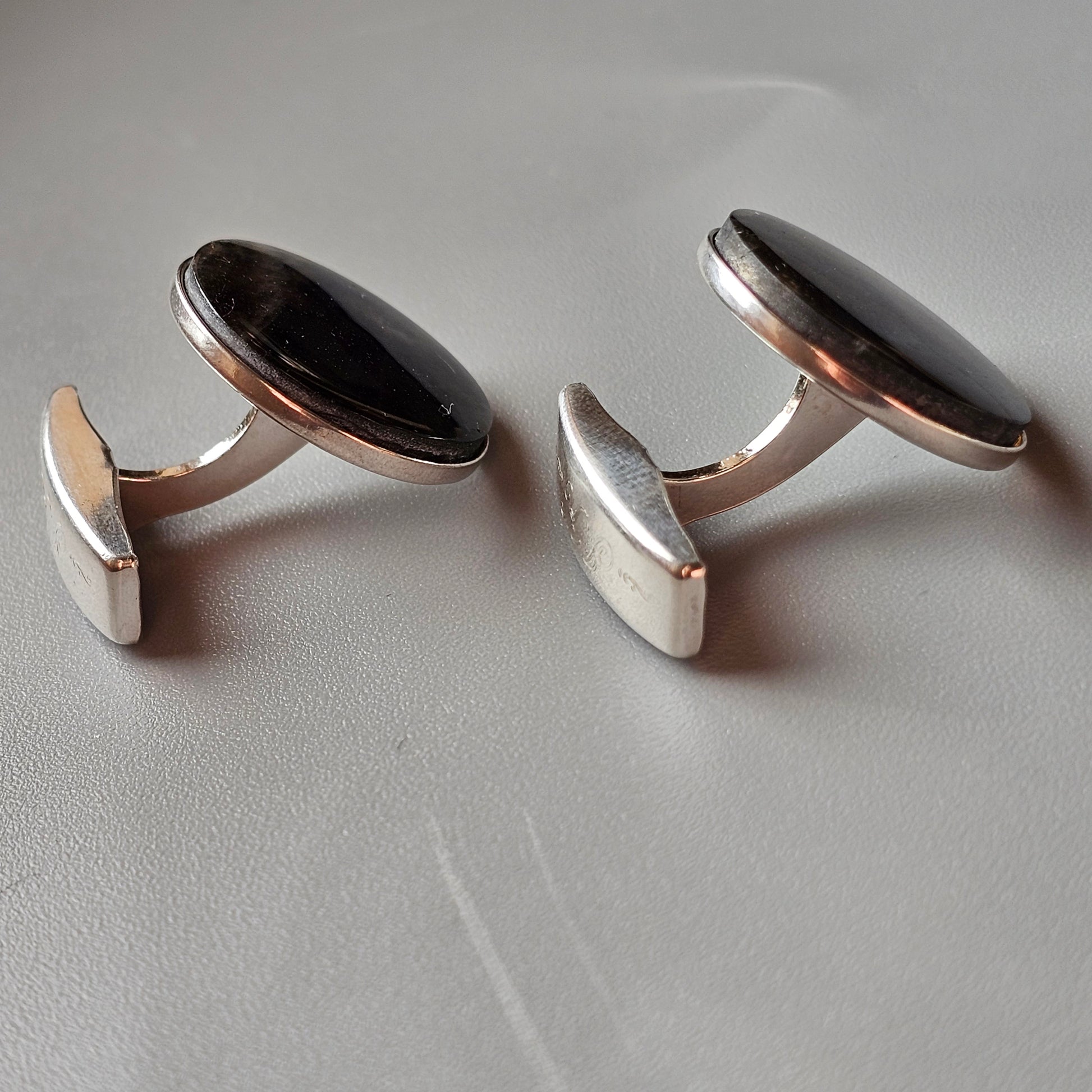 Pair of oval cufflinks with dark stones set in silver-toned metal.