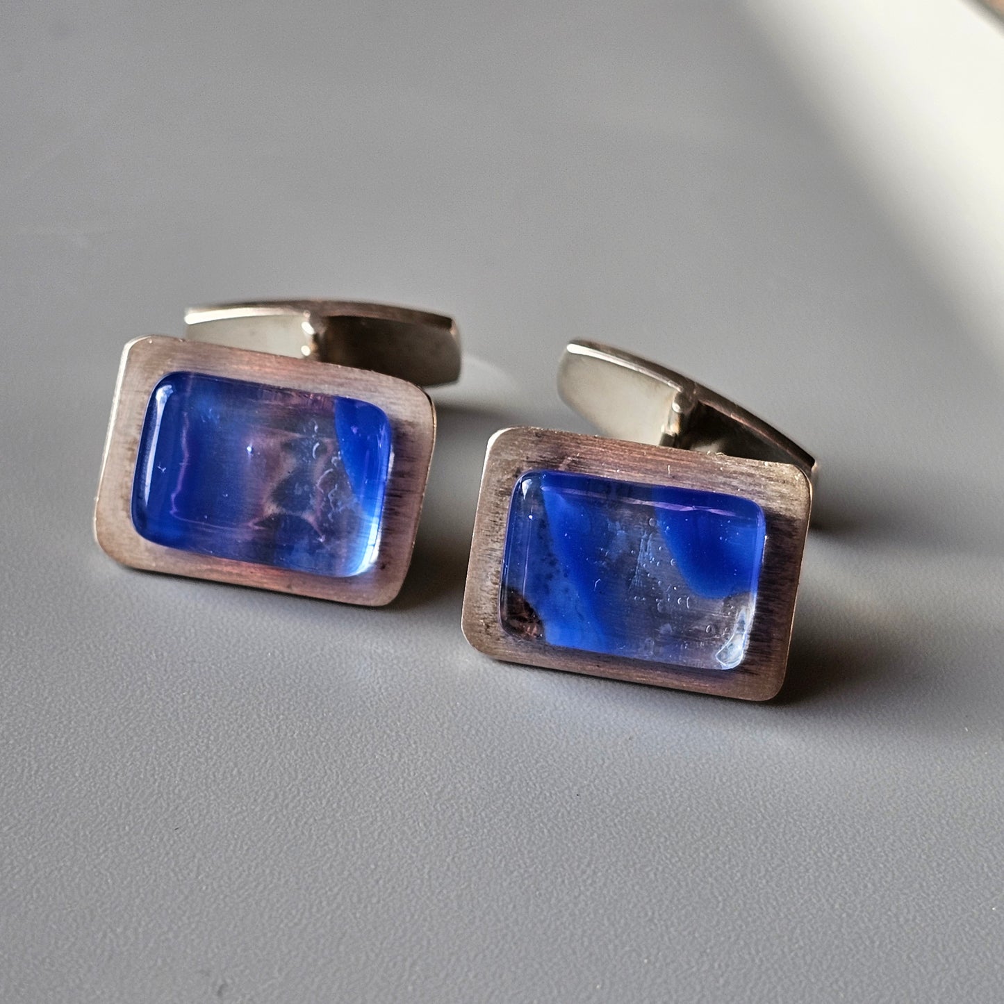 Pair of silver cufflinks with rectangular blue gemstones.