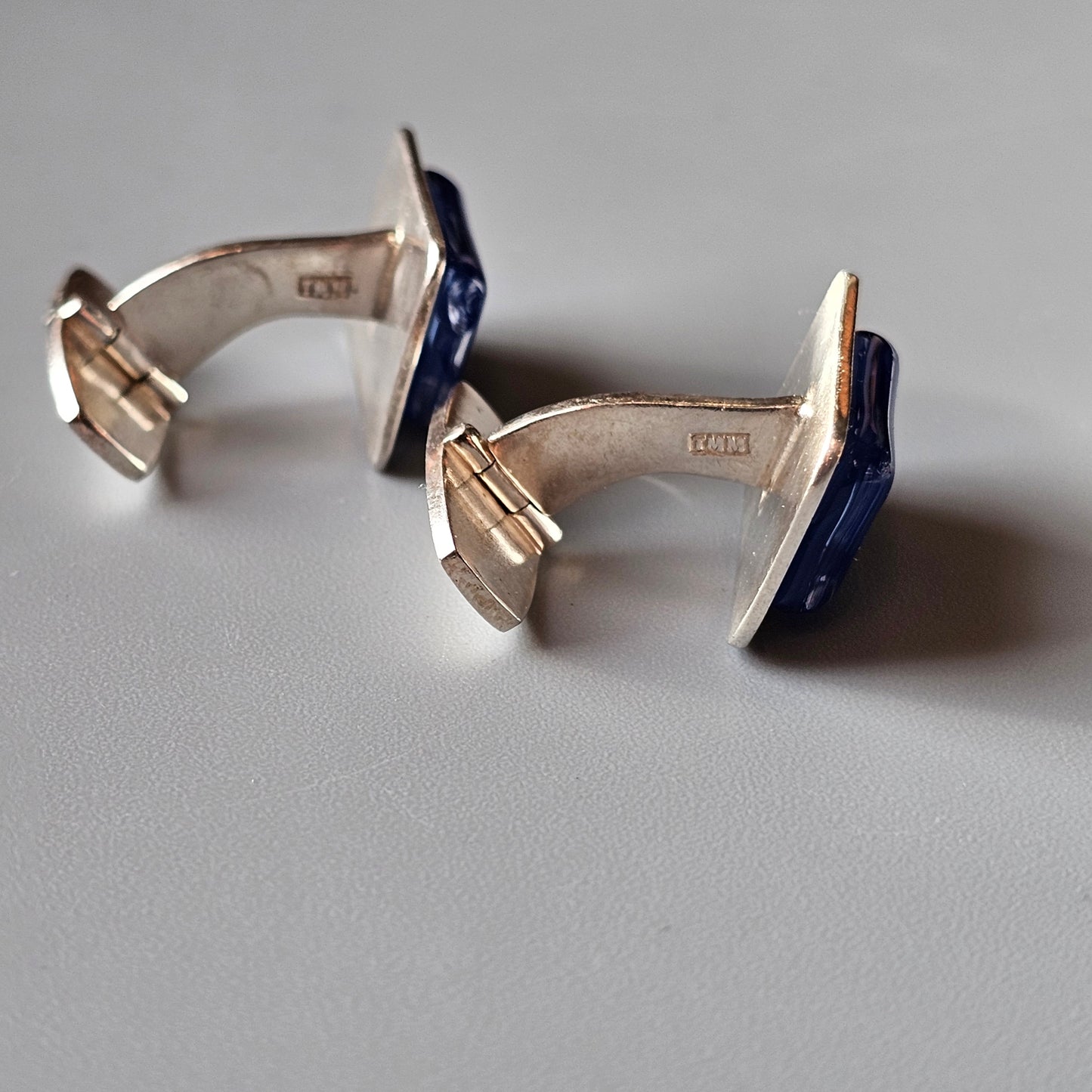 Pair of silver cufflinks with blue enamel accents.