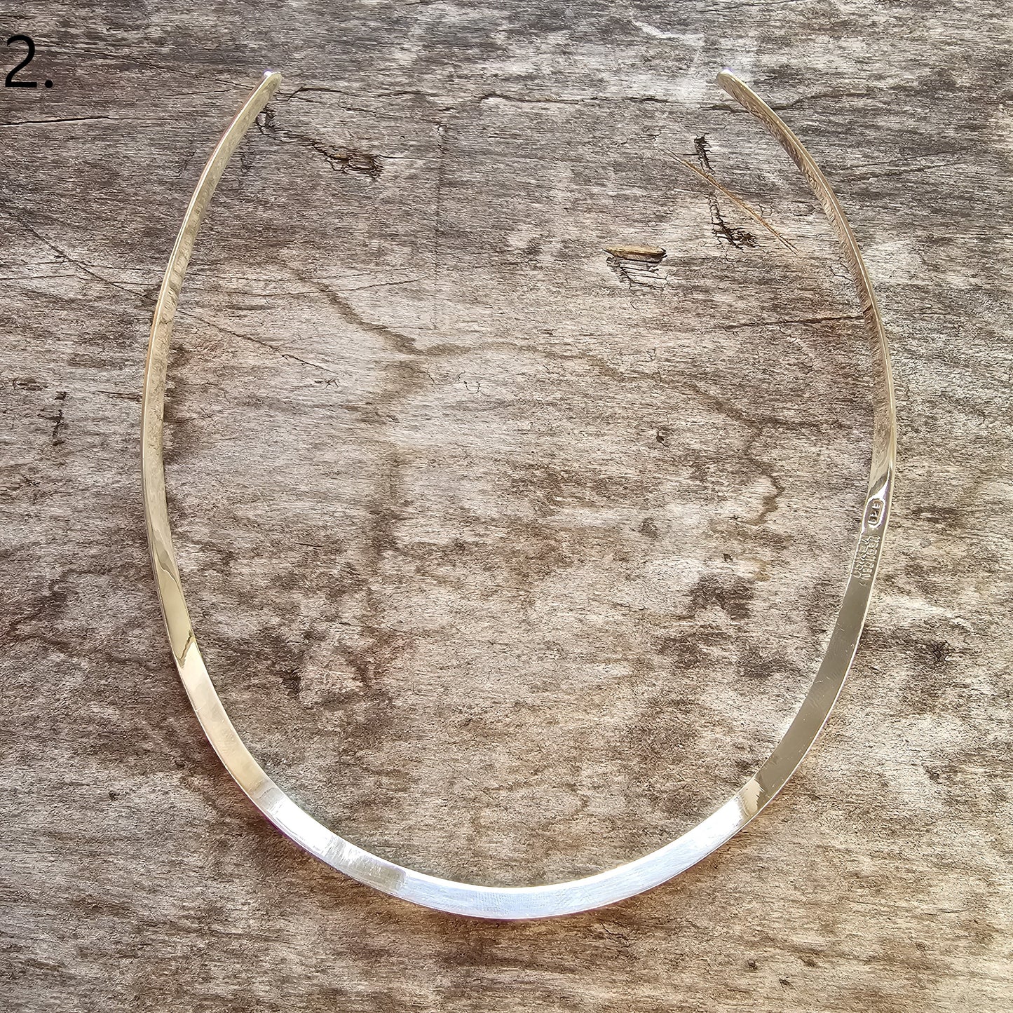 Curved, thin metal collar or necklace with a sleek, minimalist design.