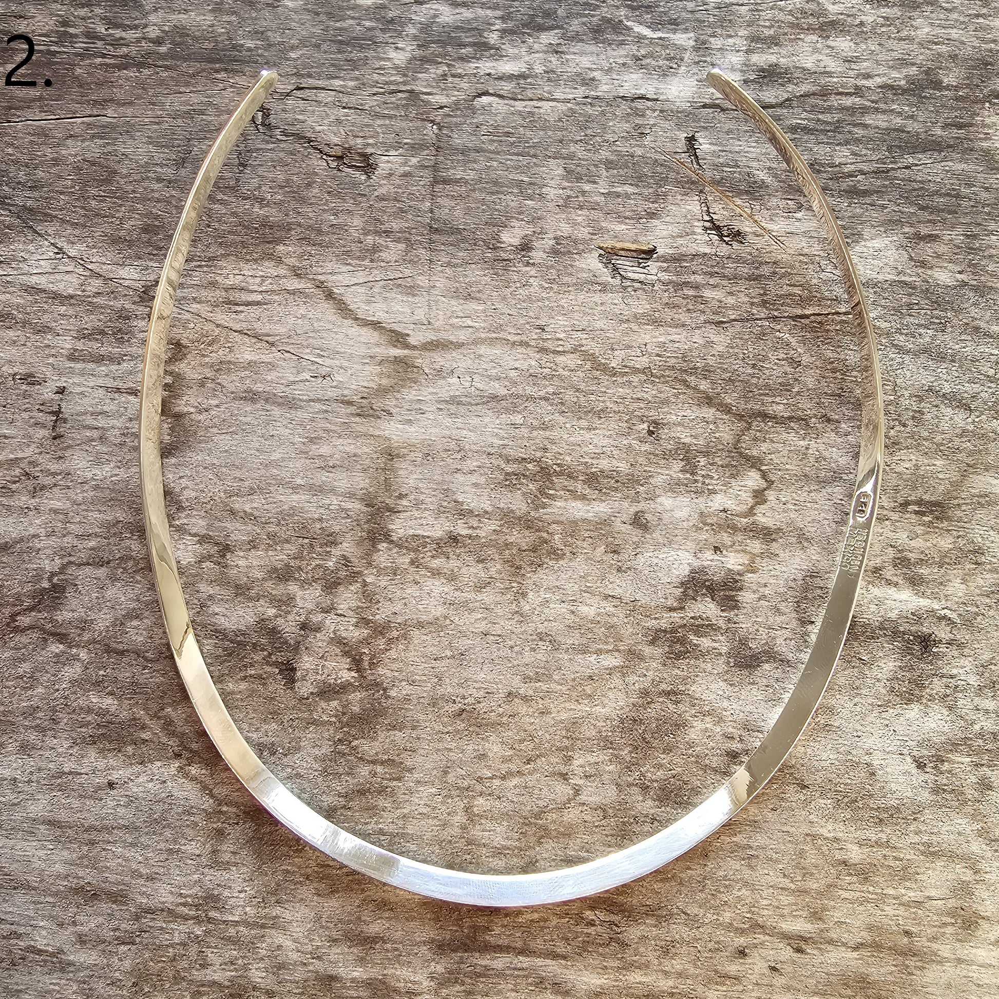 Curved, thin metal collar or necklace with a sleek, minimalist design.