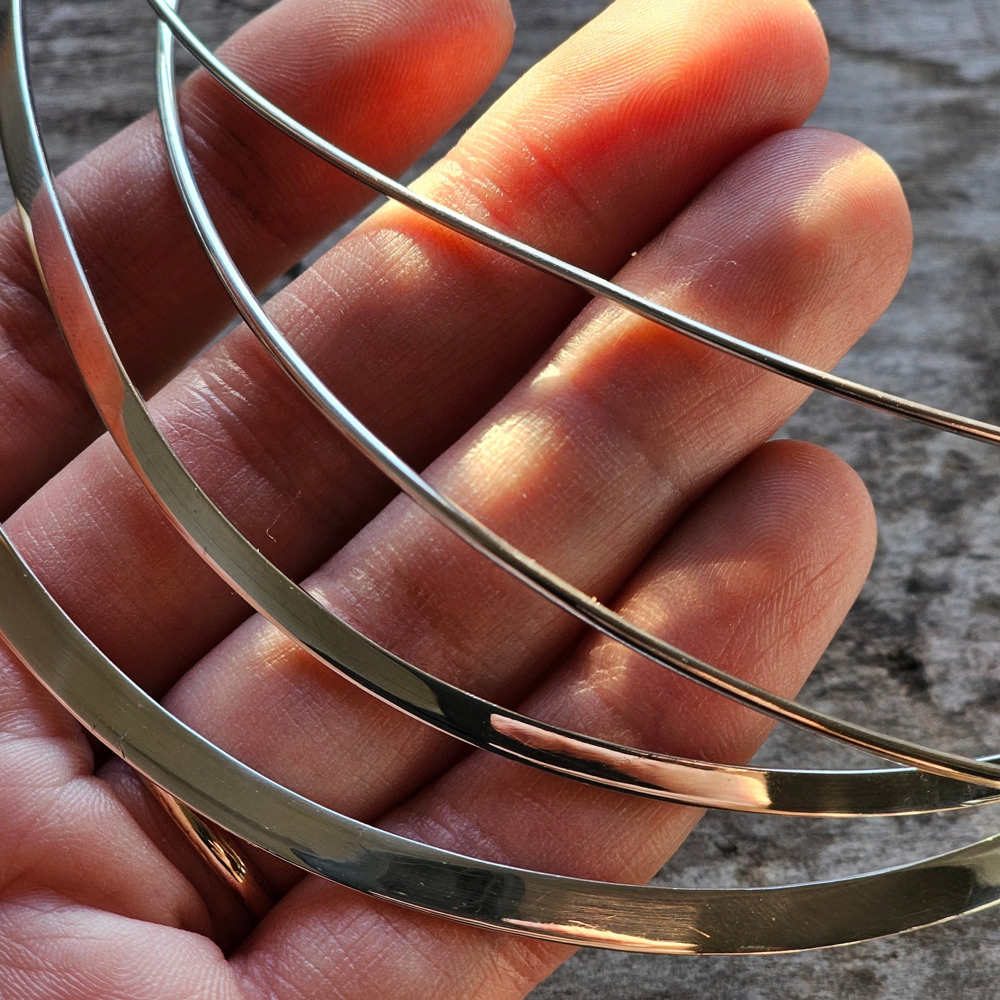 Thin metal bands or wires curved across an open palm.