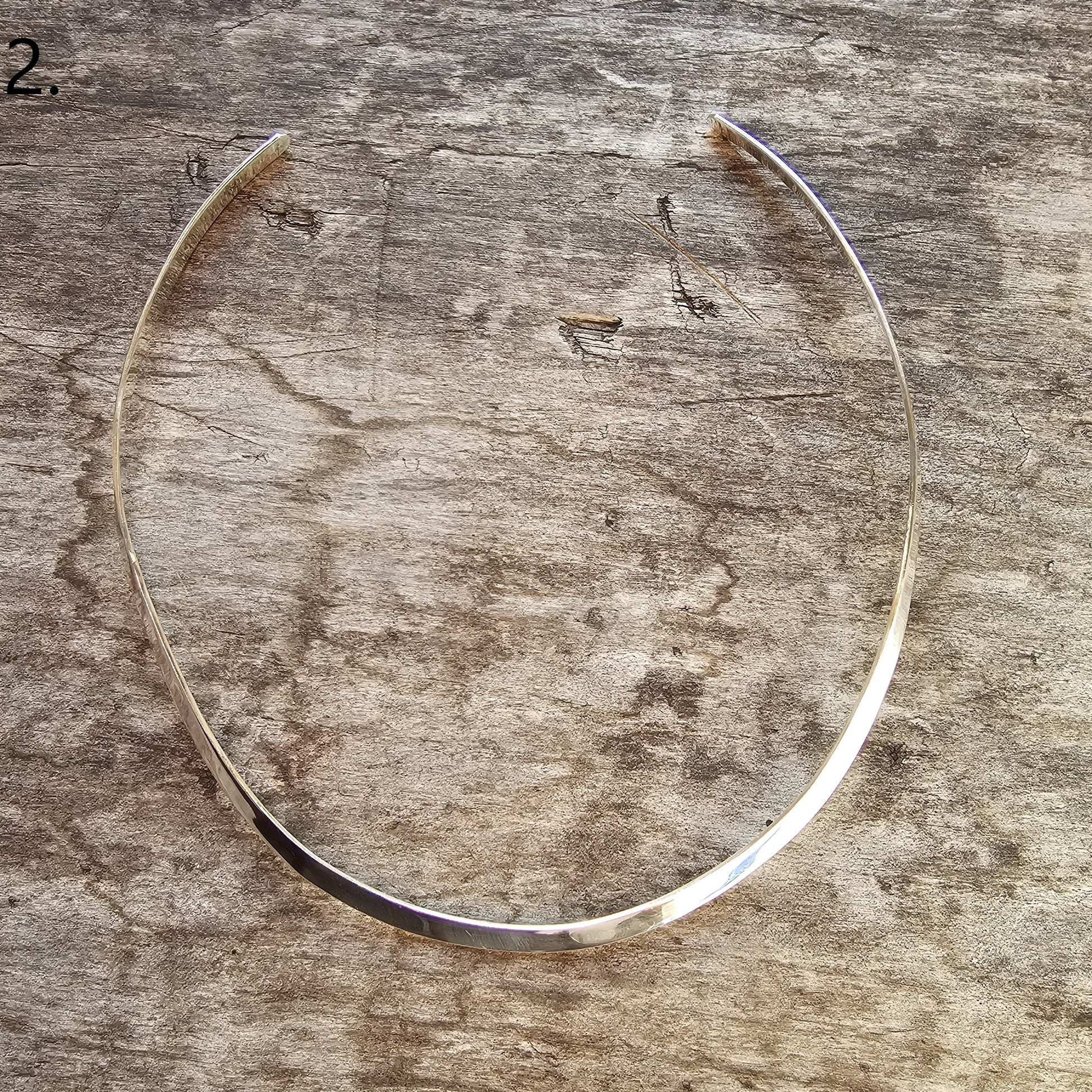 Thin, curved metal band or collar necklace.