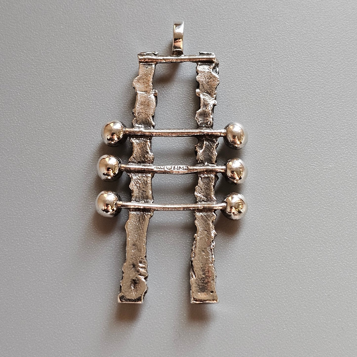 Silver pendant featuring two vertical bars connected by three horizontal rods with spherical ends.