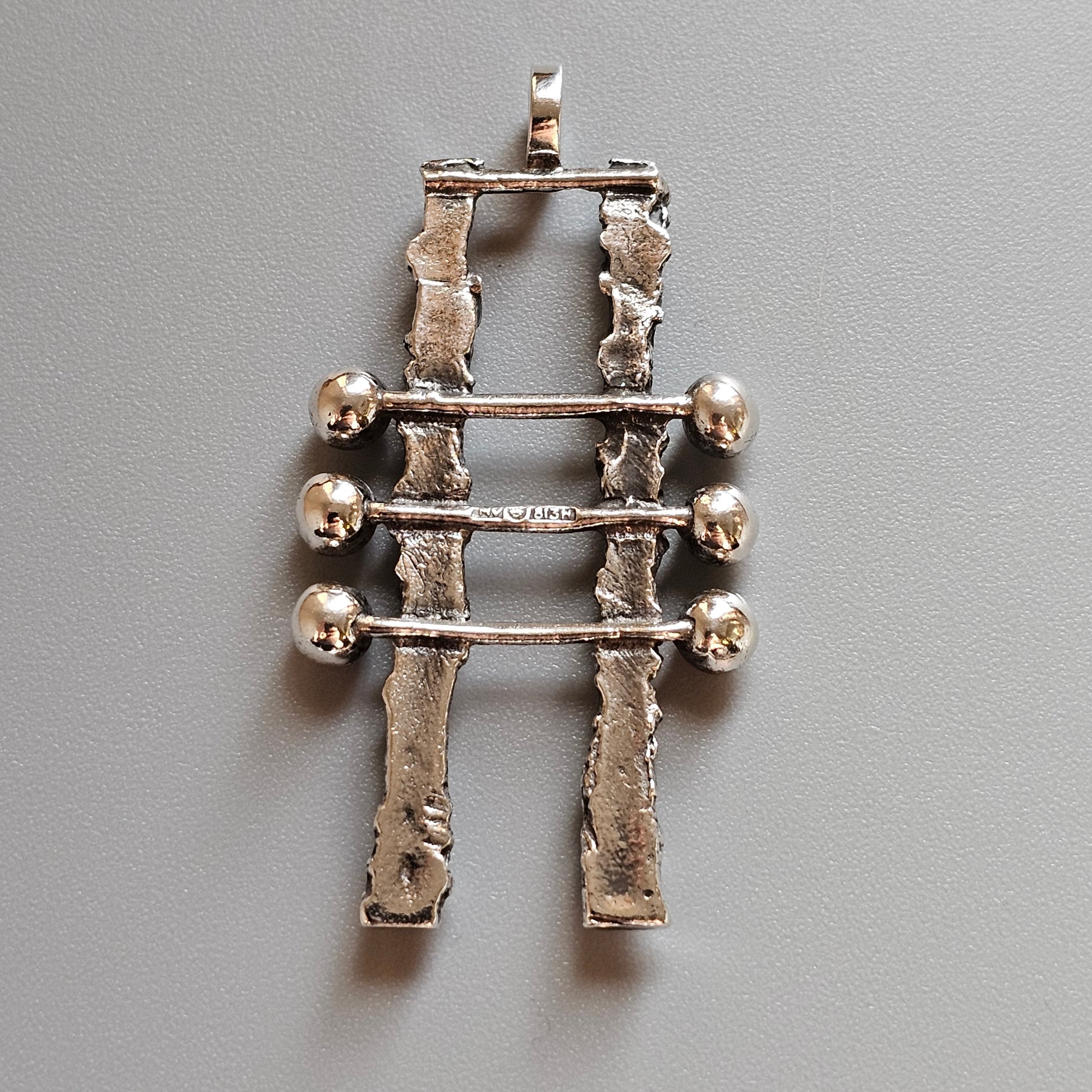 Silver pendant featuring two vertical bars connected by three horizontal rods with spherical ends.