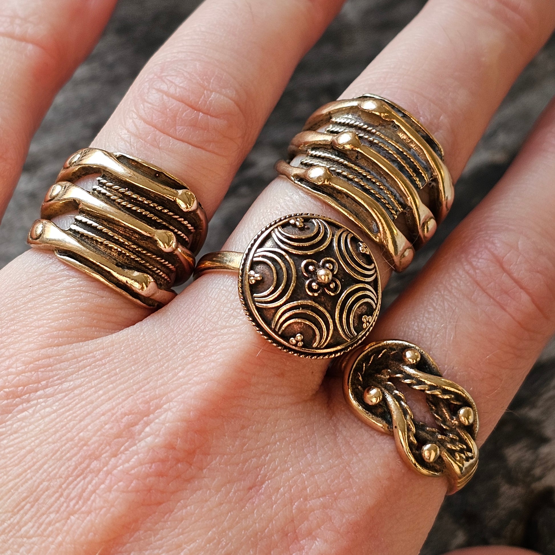 Collection of ornate gold-toned rings worn on fingers.