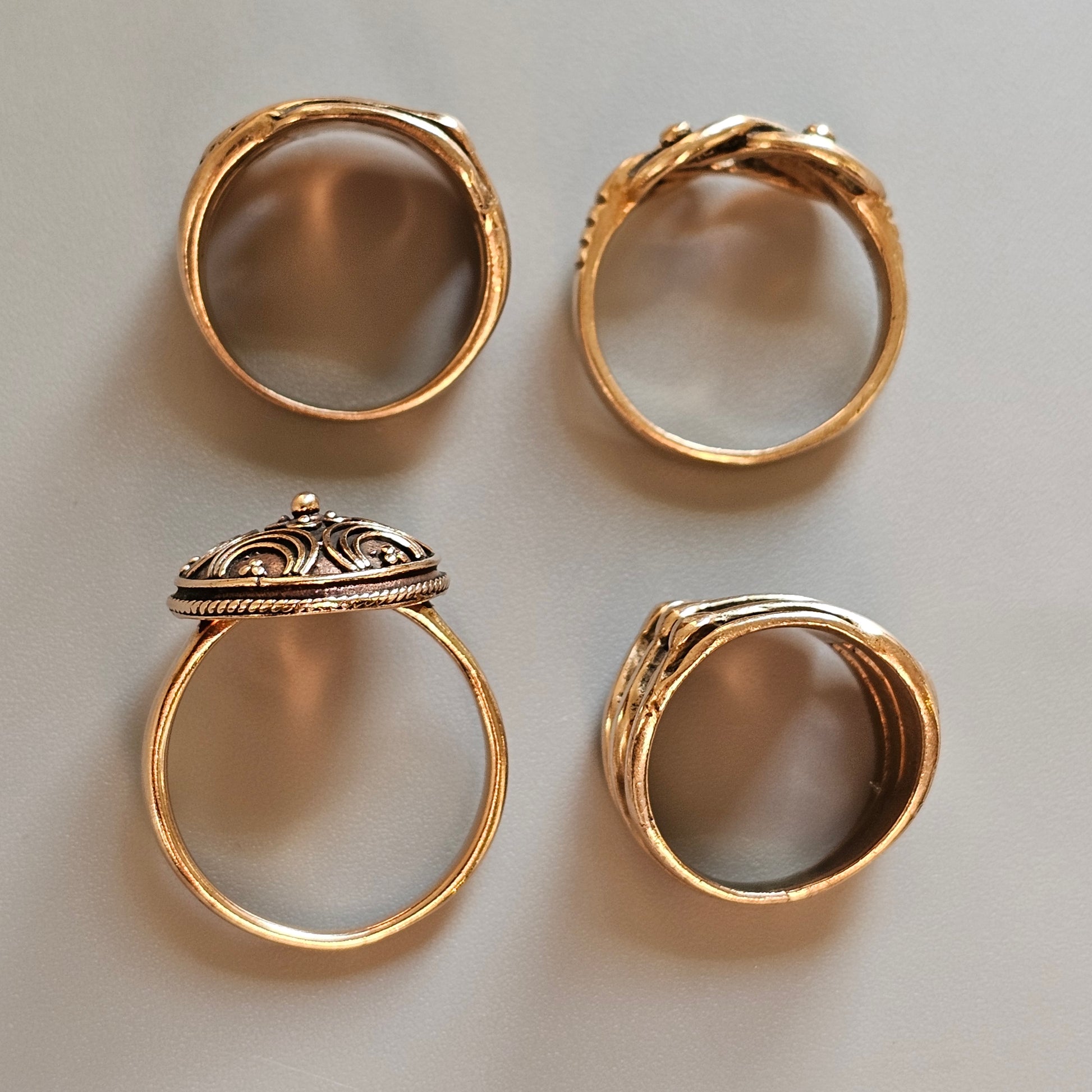 Four gold rings with different decorative designs.