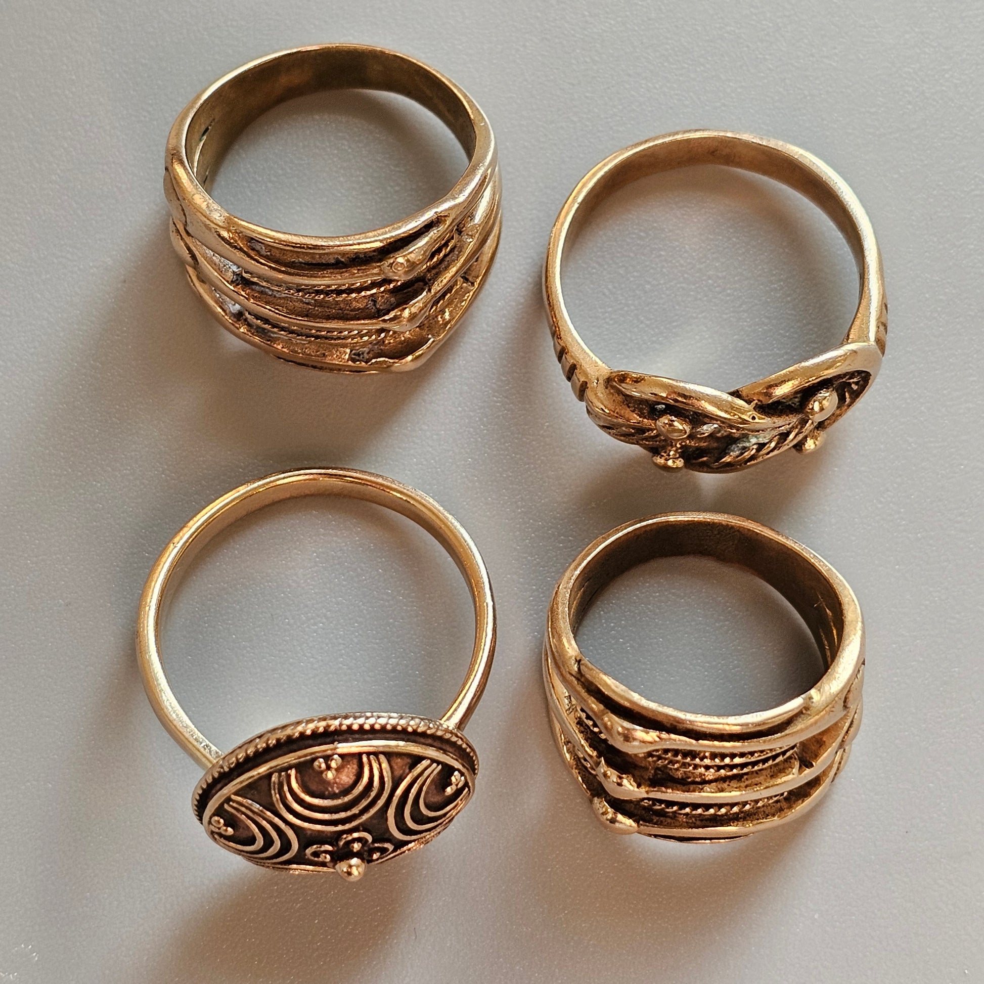 Four ornate gold rings with intricate designs and patterns.