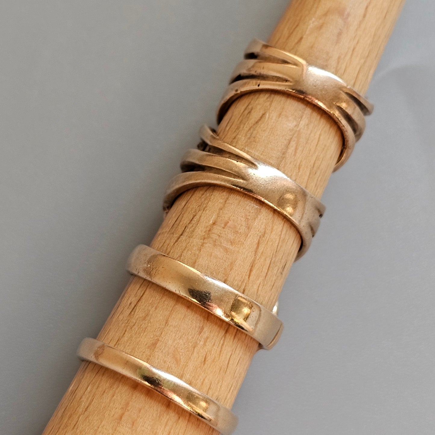 Gold-colored metal rings stacked on a wooden surface.