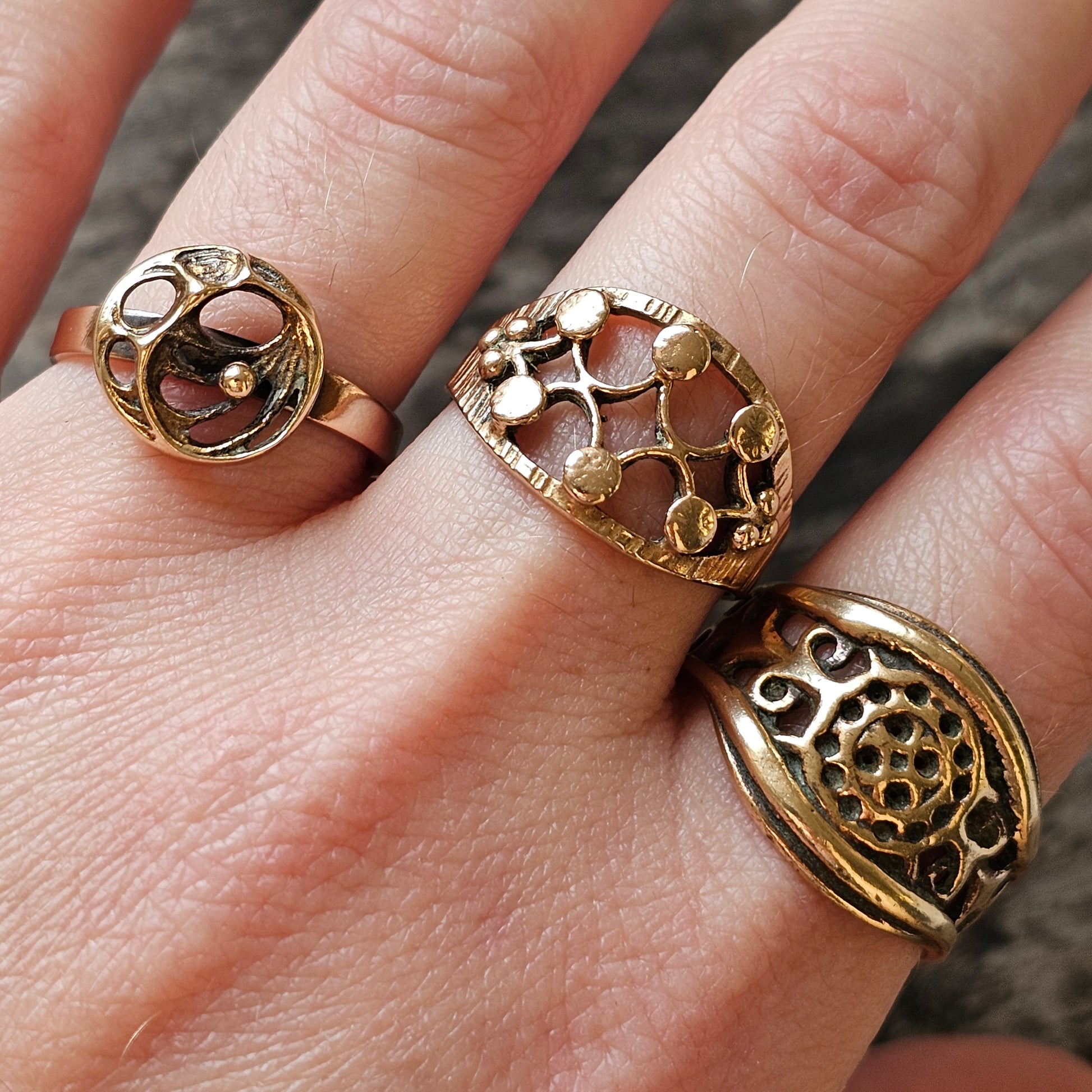 Three ornate gold rings worn on fingers.