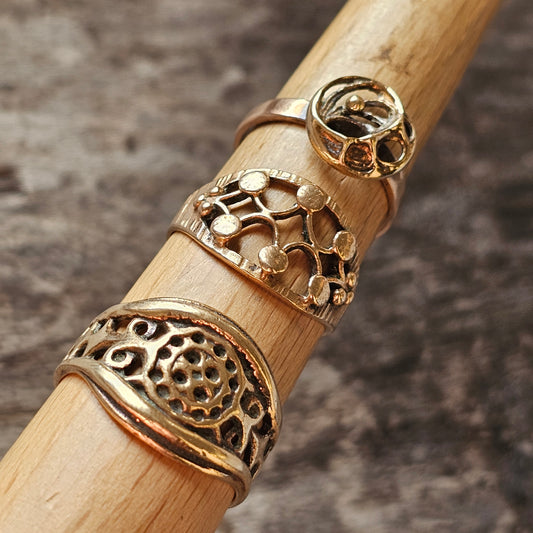 Wooden dowel or rod displaying three ornate gold rings with intricate designs.