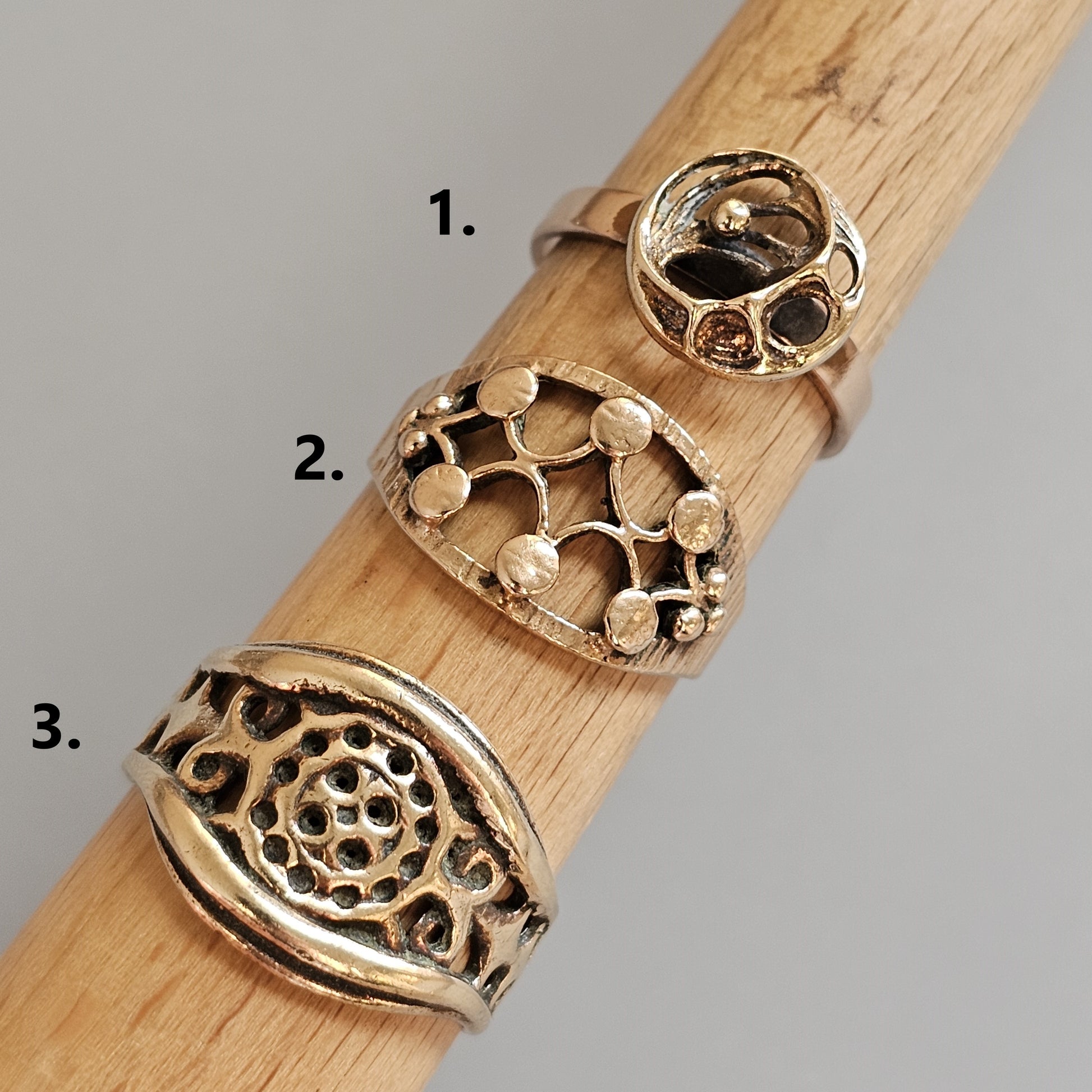 Wooden dowel or rod displaying three different decorative metal rings.