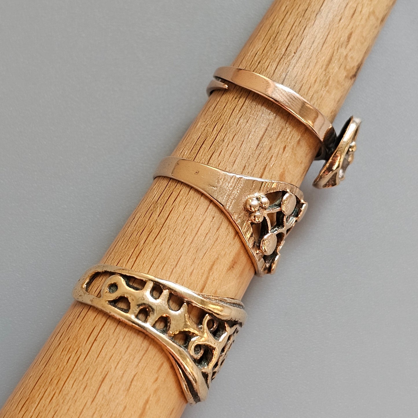 Gold rings with various designs displayed on a wooden surface.