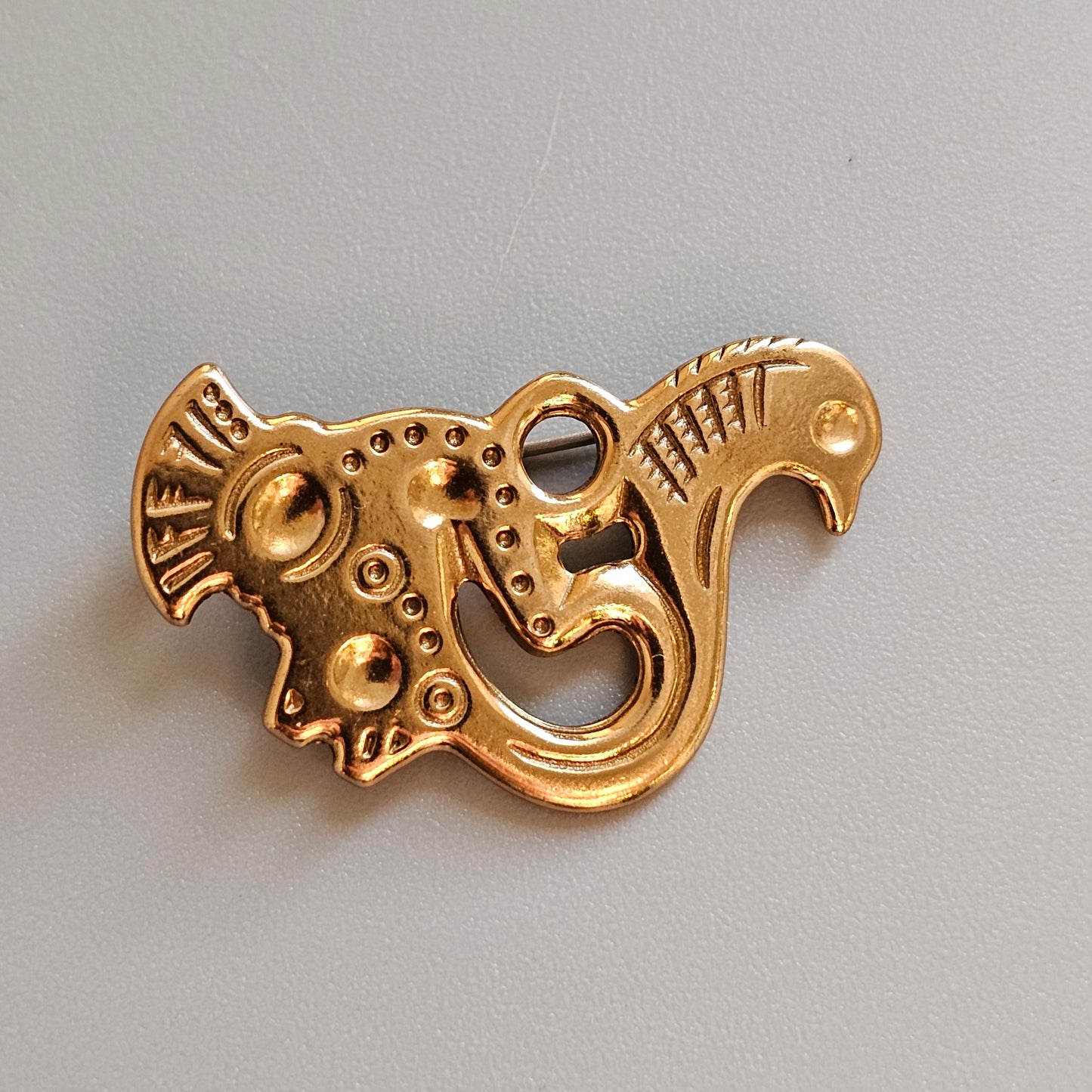 Golden ornament shaped like a stylized mythical creature or fish with intricate details.