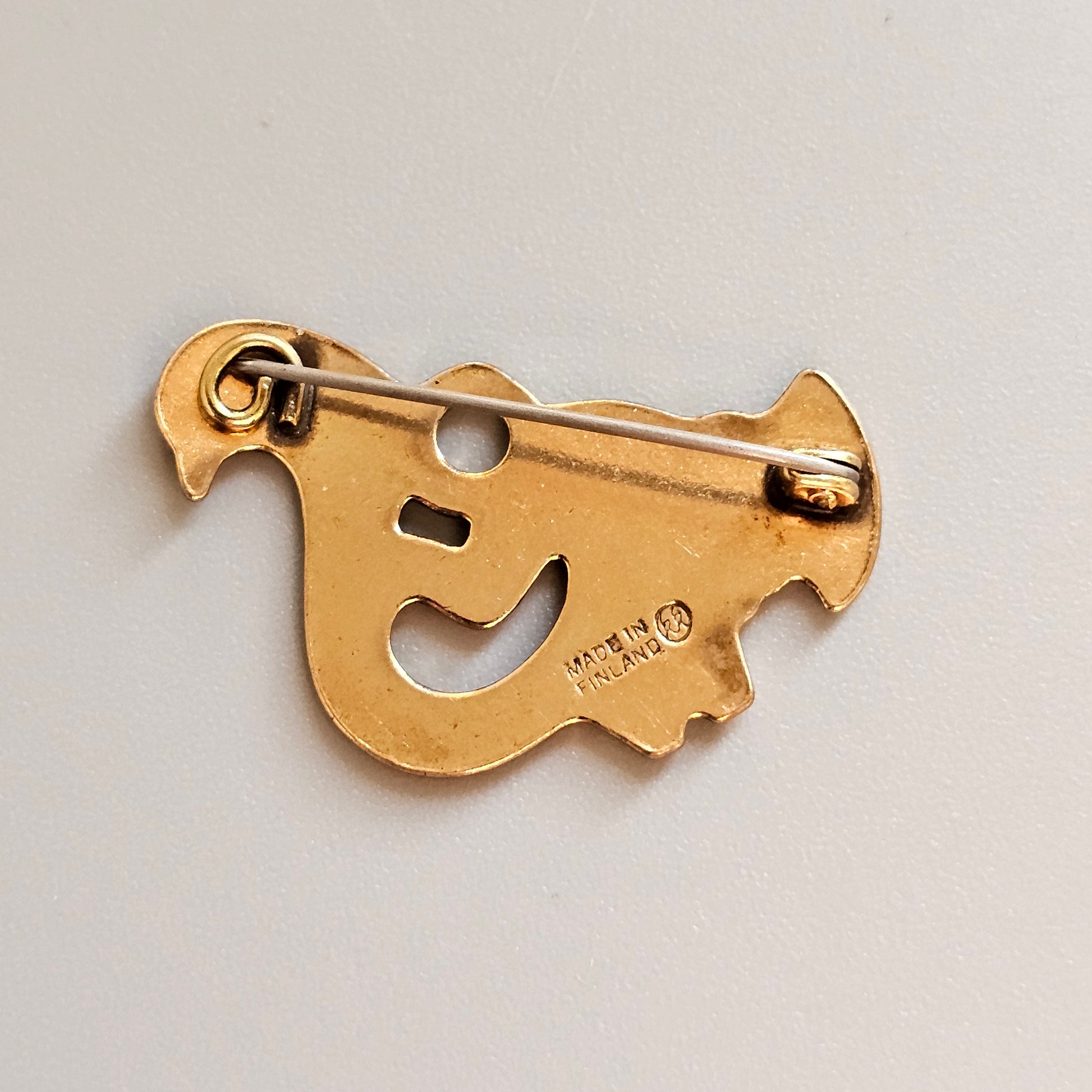 Gold-colored metal bottle opener shaped like a stylized bird or animal.