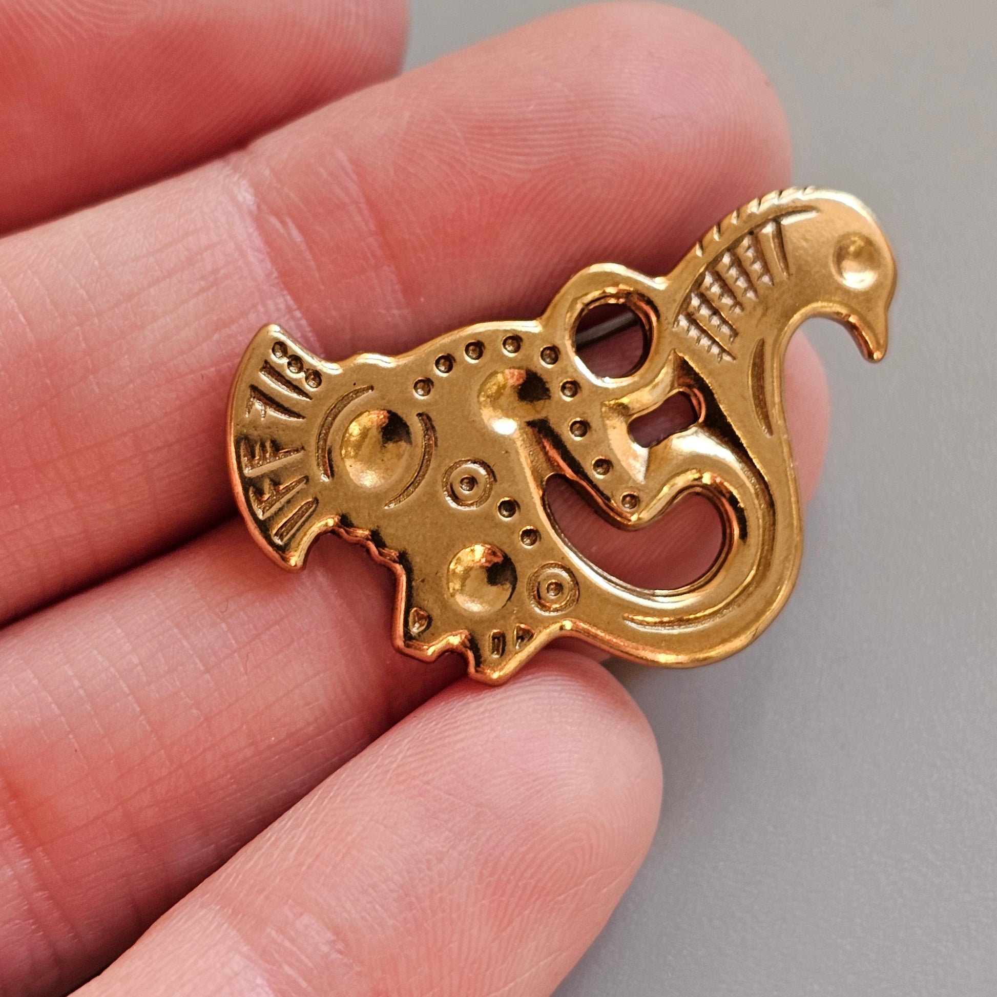 Golden ornate pendant shaped like a stylized bird or dragon.