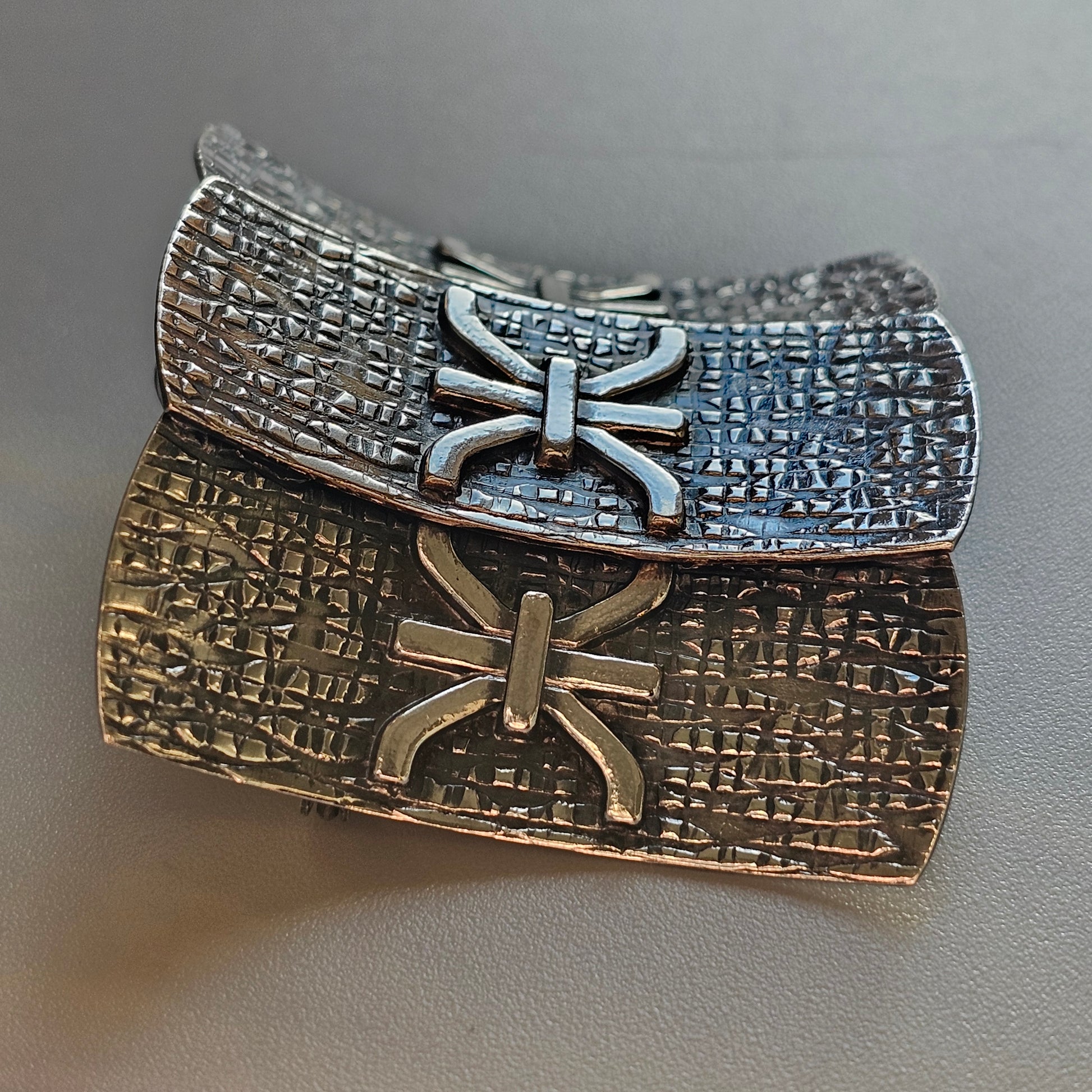 Ancient-looking metal artifact with inscribed symbols and decorative bow-like shapes.