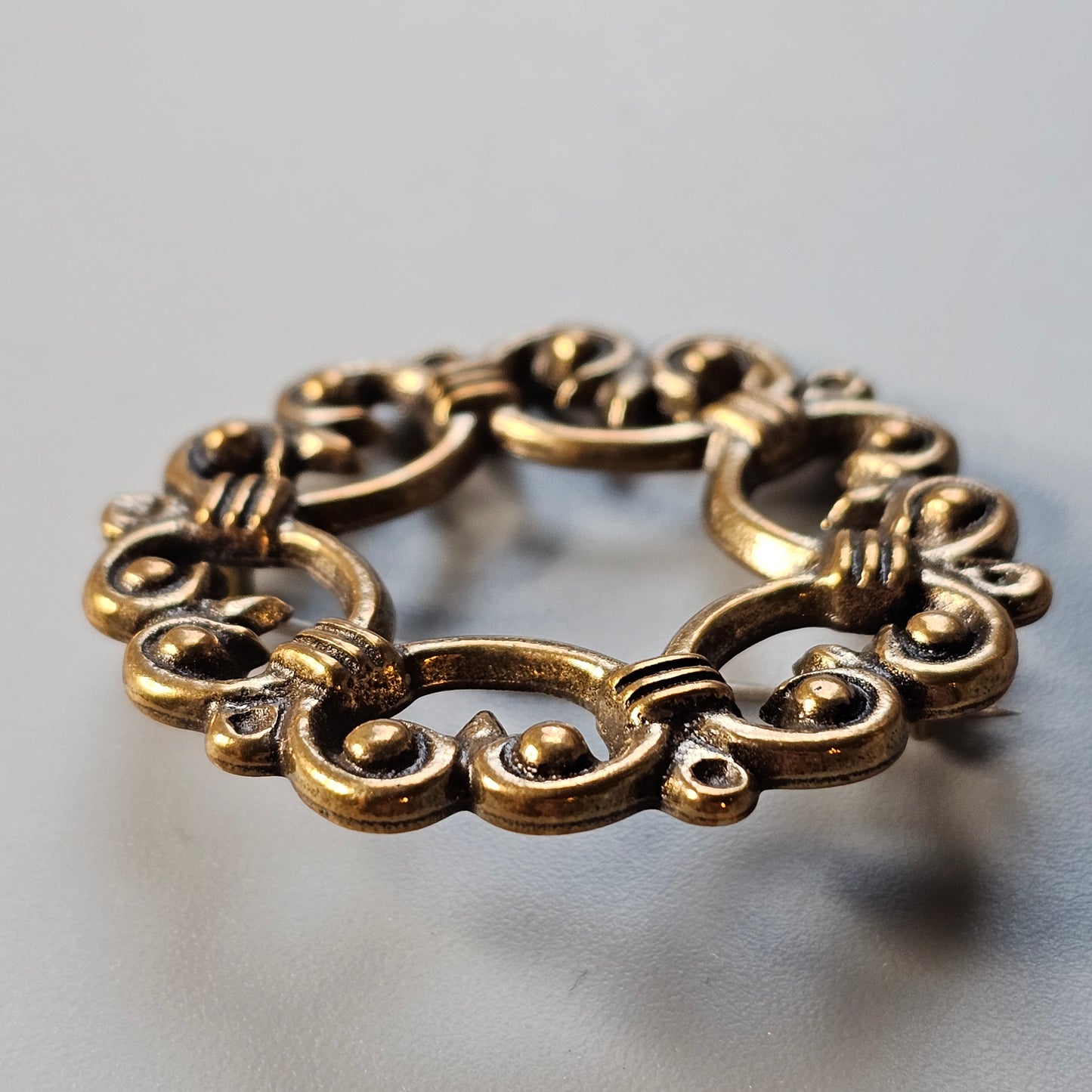 Ornate gold-toned metal ring with intricate swirling patterns.