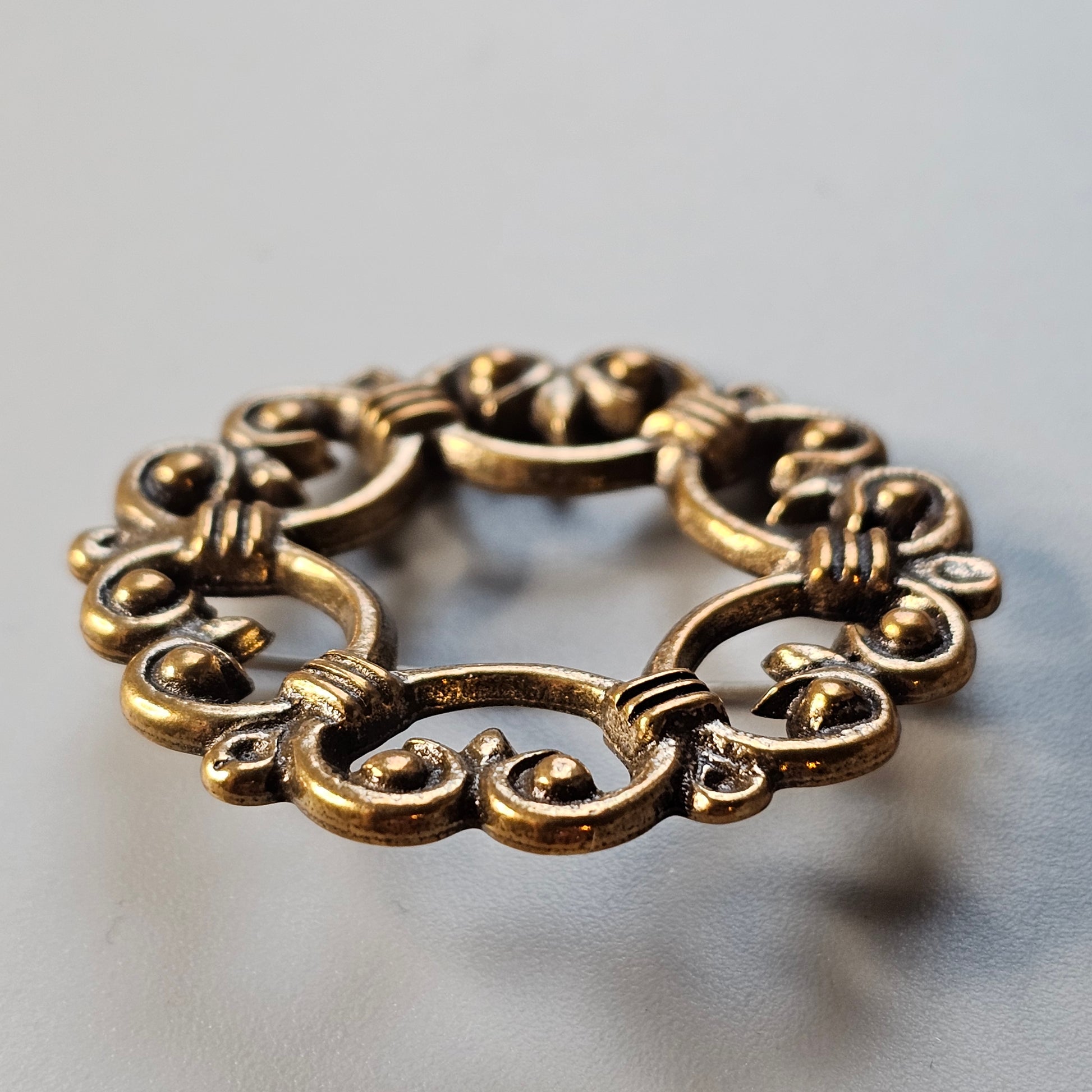 Ornate gold-toned metal bracelet with intricate swirling designs forming circular links.