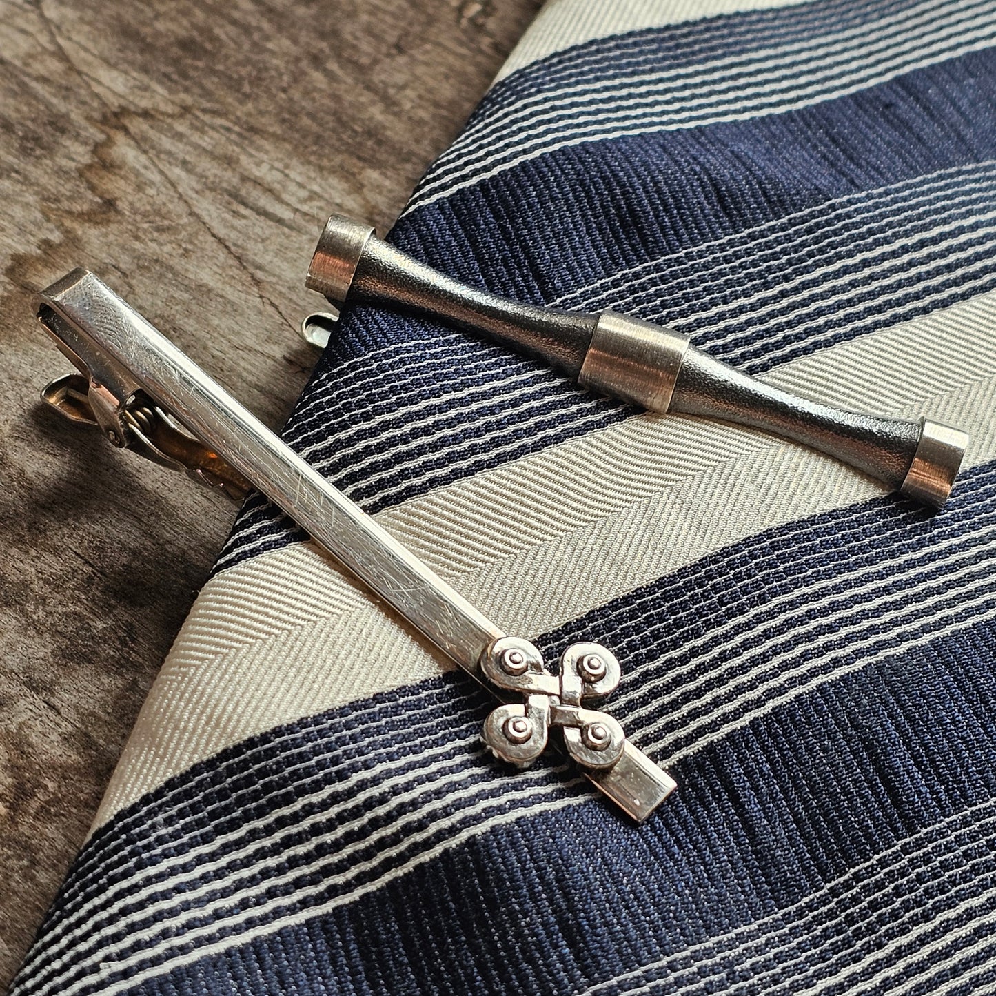 Vintage tie clip and tie bar set on a striped necktie.