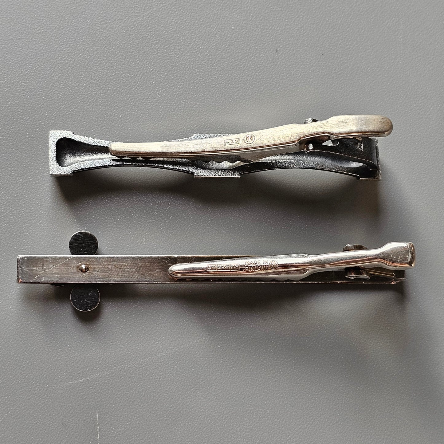 Two metal hair clips or barrettes with hinged designs.