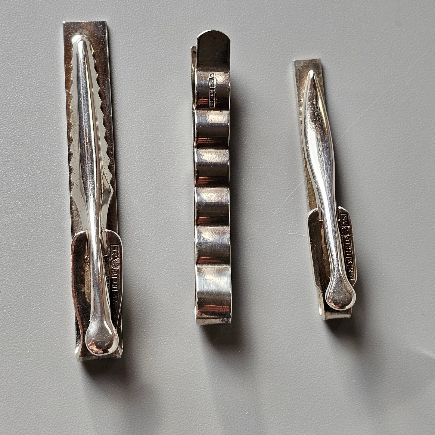 Three metal hair clips or barrettes arranged side by side.