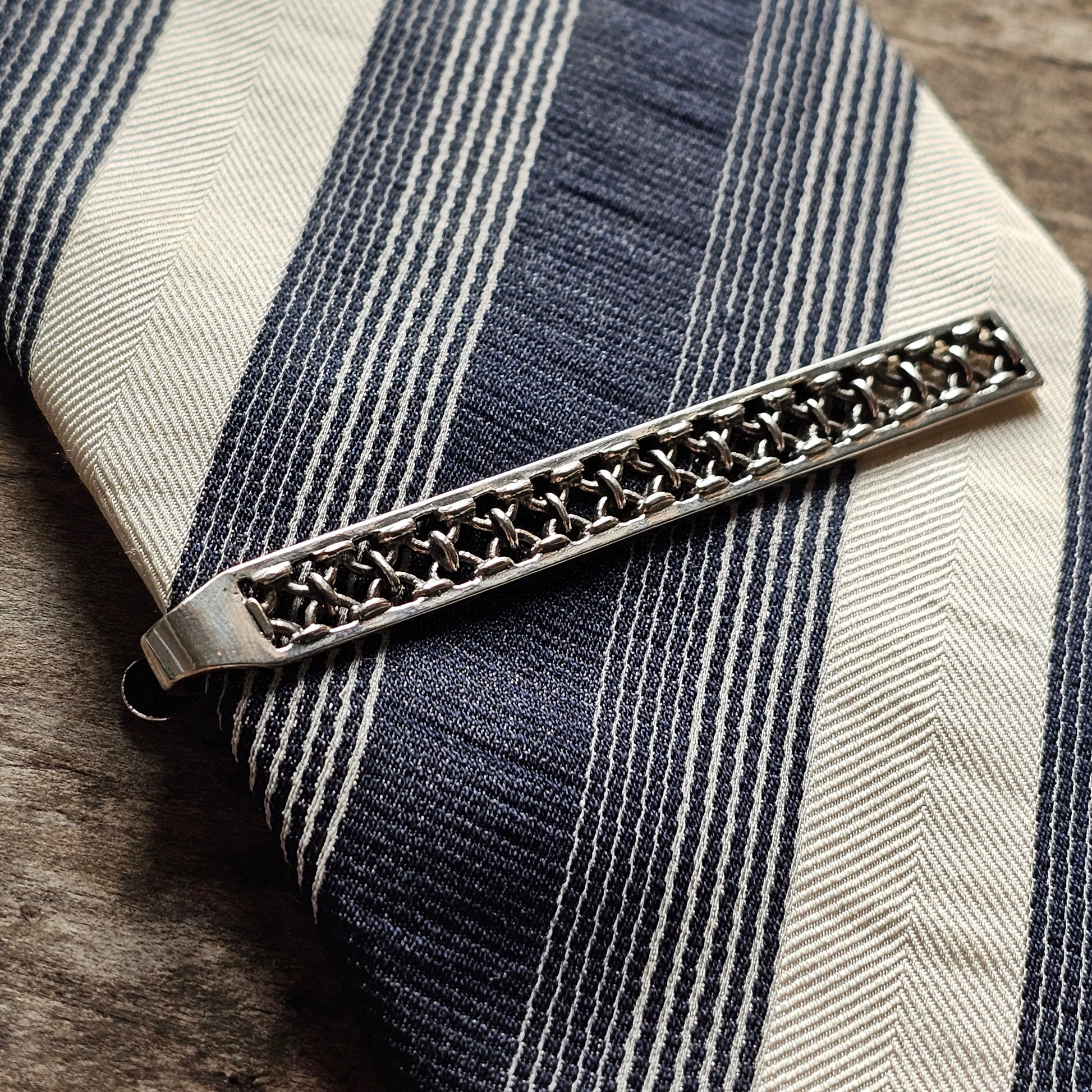 Decorative silver tie clip with an intricate lattice pattern.