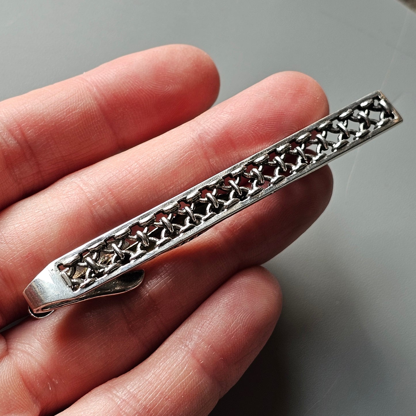 Ornate silver tie clip with a star-patterned design.