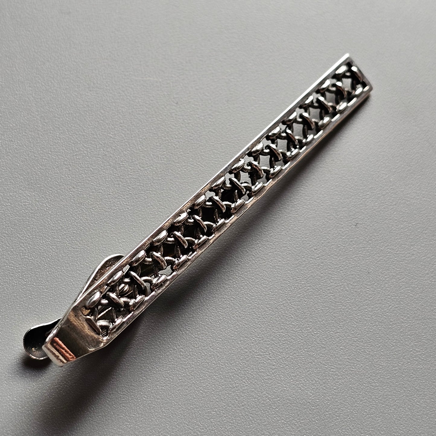 Ornate silver tie clip with intricate filigree design.