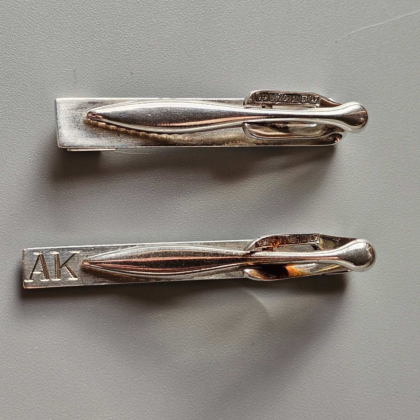 Two silver tie clips with sleek, elongated designs.