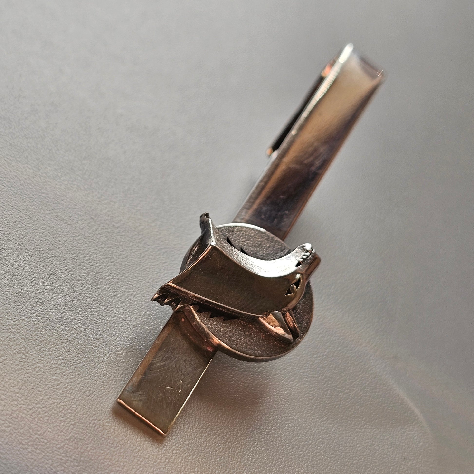 Metal tie clip with a distinctive horseshoe-shaped design.