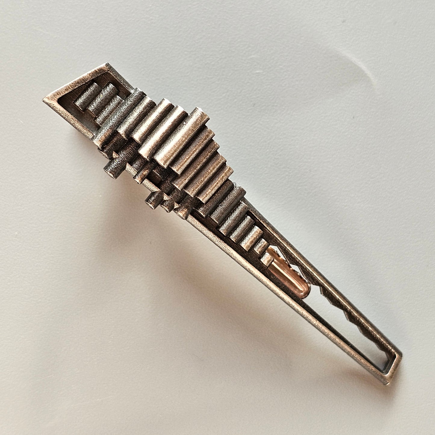 Metallic hair clip with a geometric, stepped design resembling an Art Deco skyscraper.