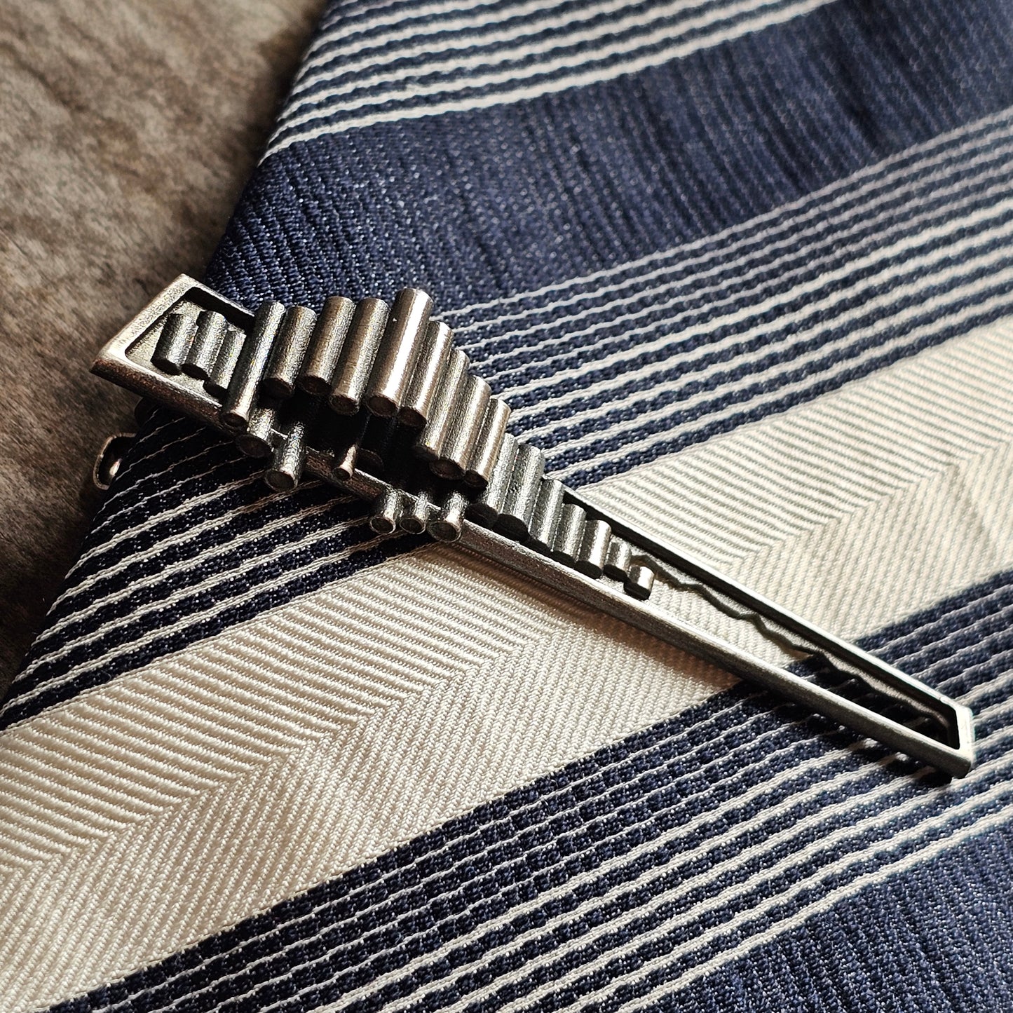 Silver tie clip with a geometric, ridged design.