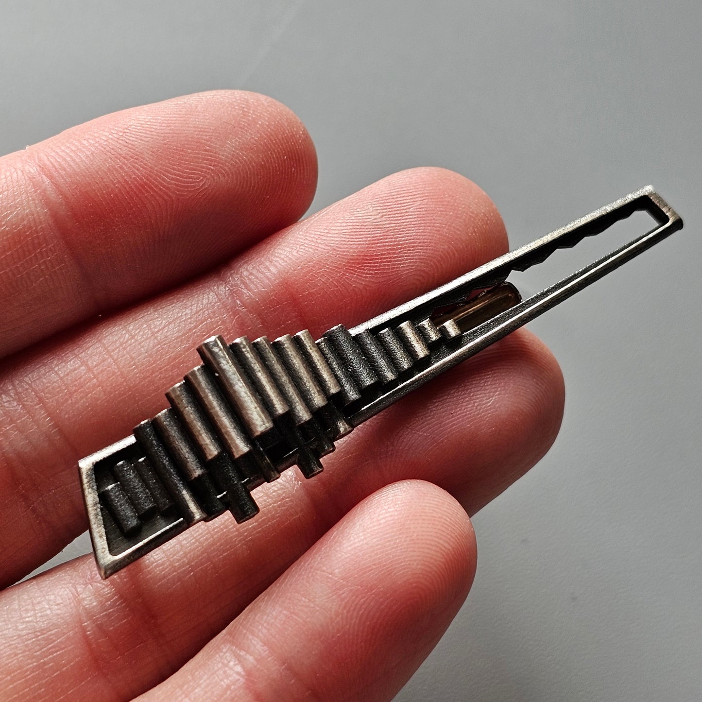 Metallic tie clip shaped like a piano keyboard.