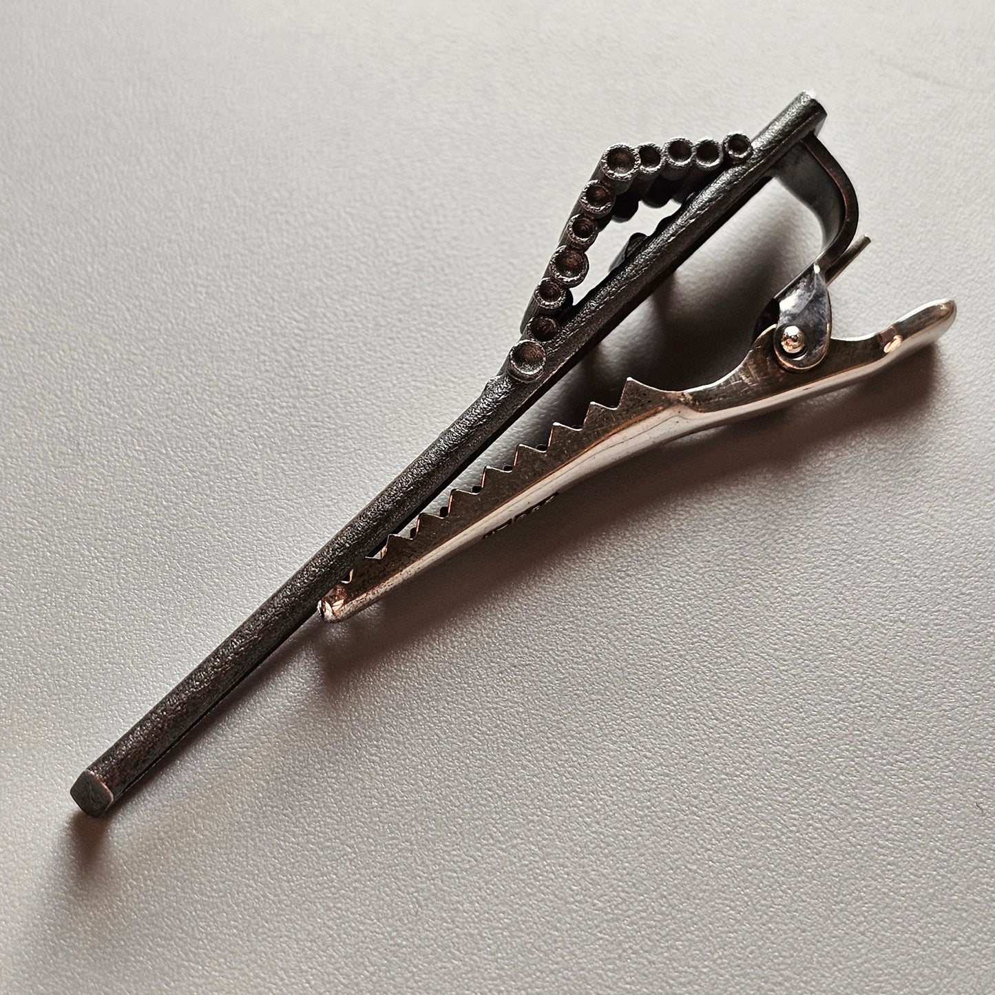 Hair clip with a textured, elongated design featuring small circular embellishments.