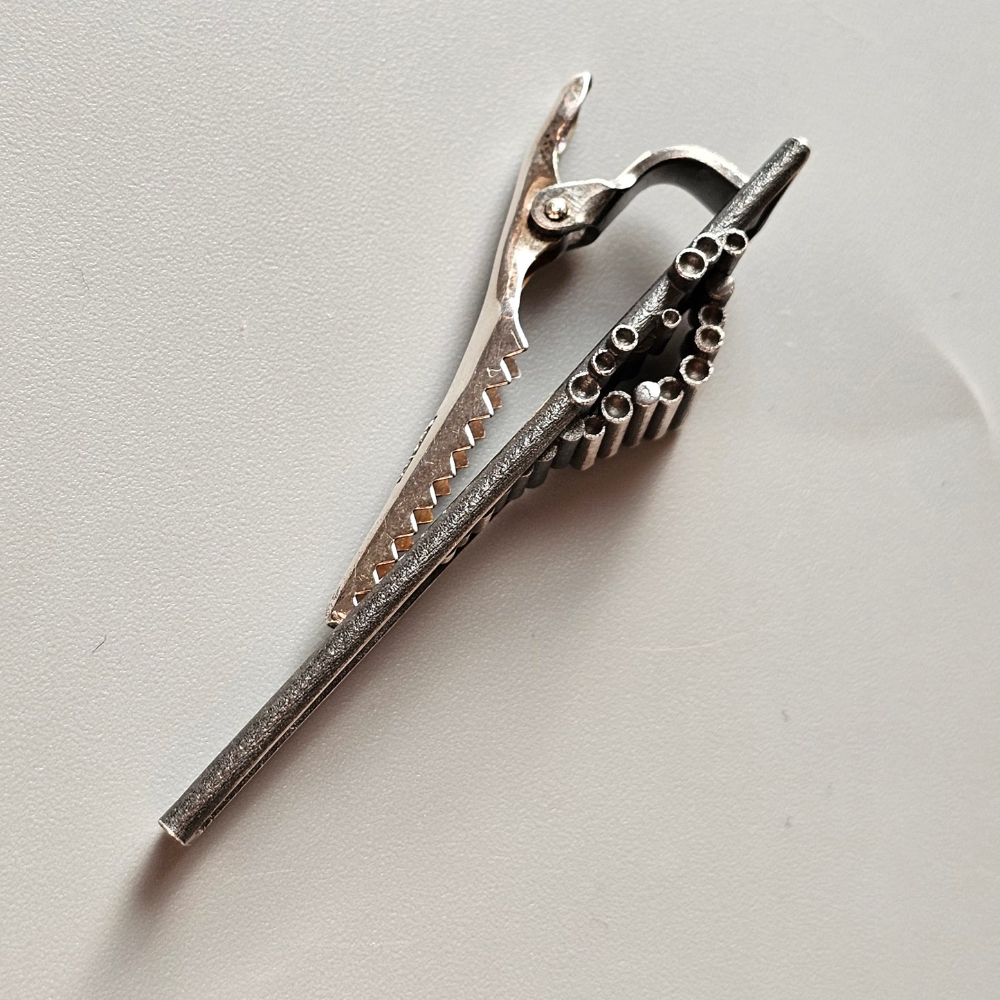 Metal hair clip with a serrated edge and spring mechanism.