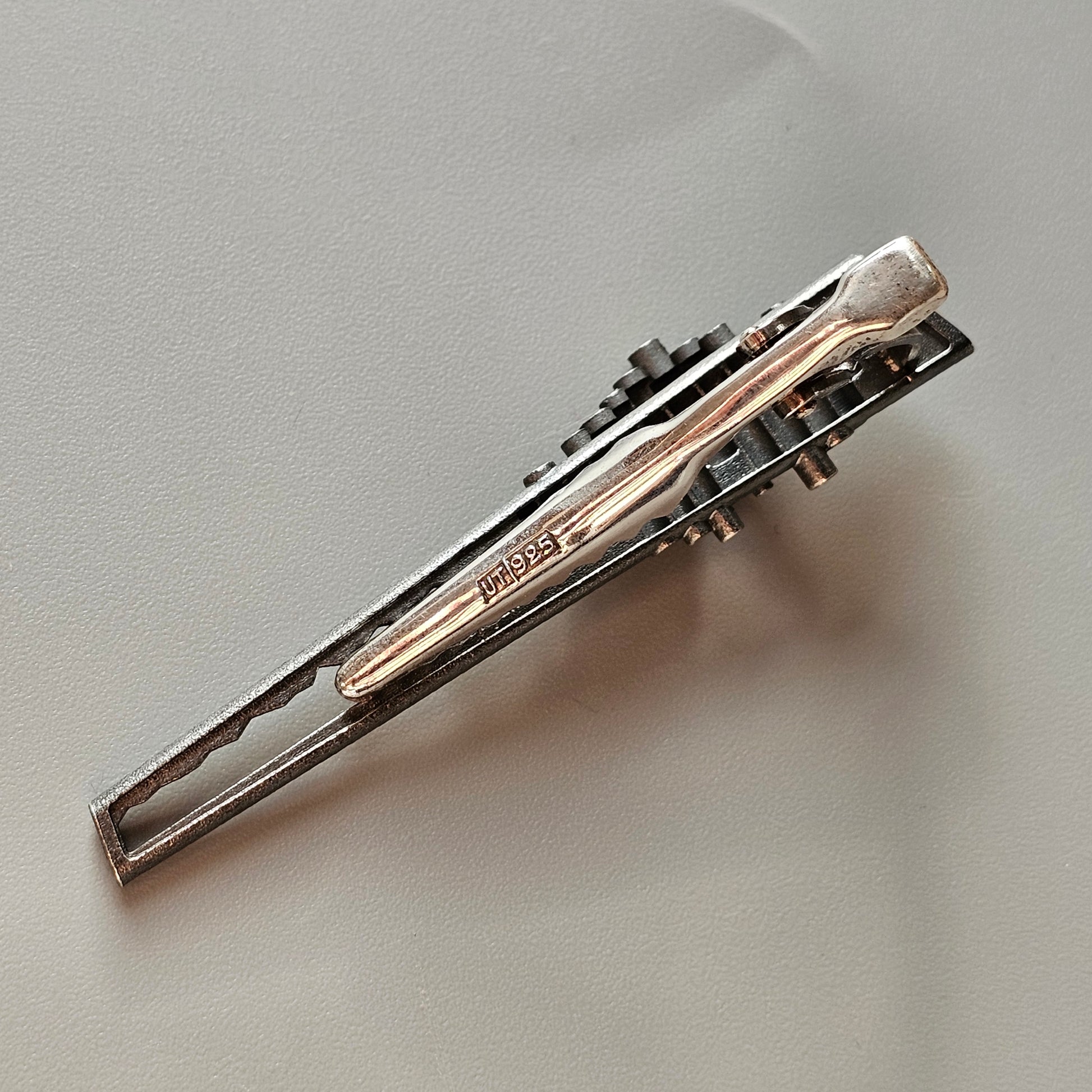 Silver tie clip with decorative black accents.