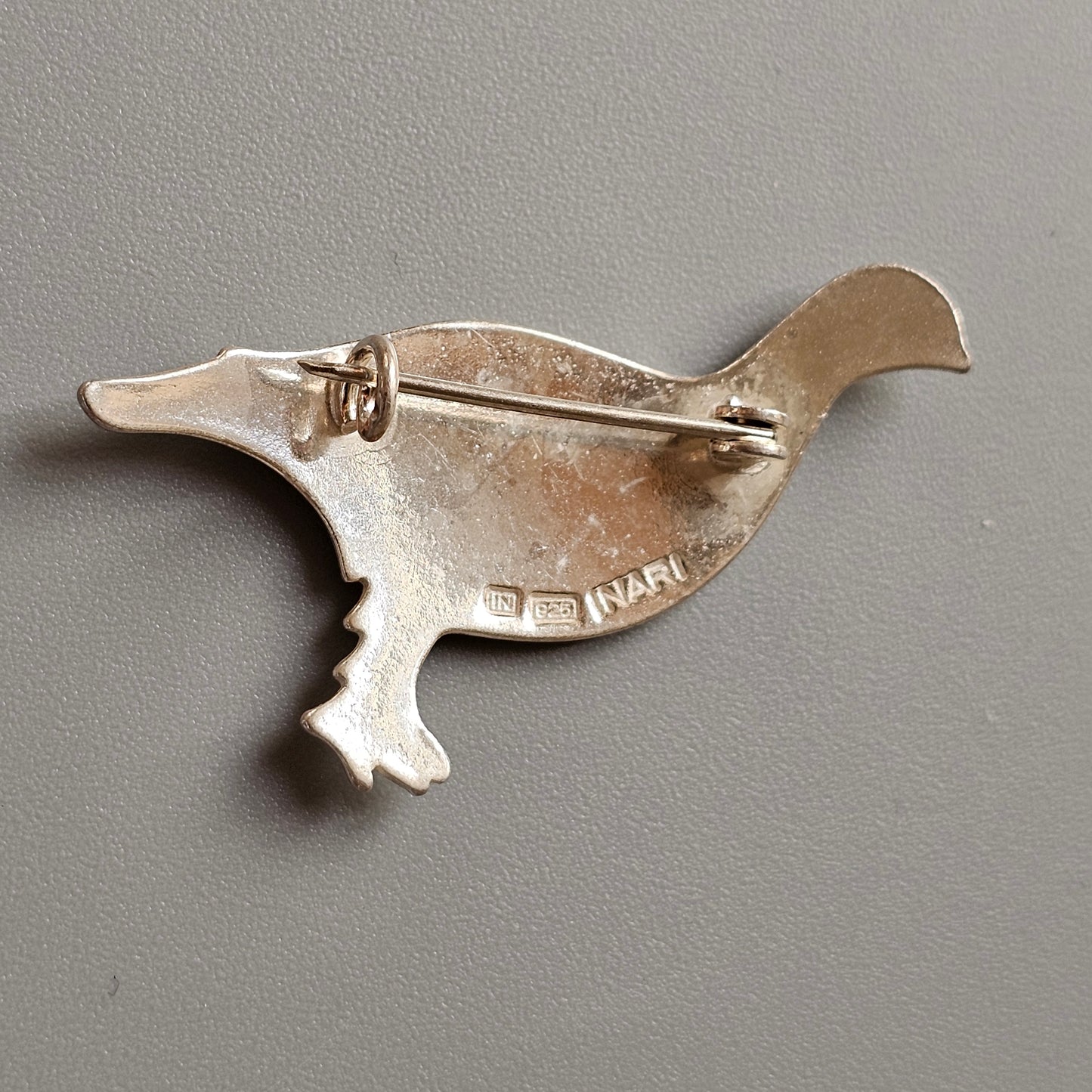 Silver brooch shaped like a stylized duck or waterfowl.