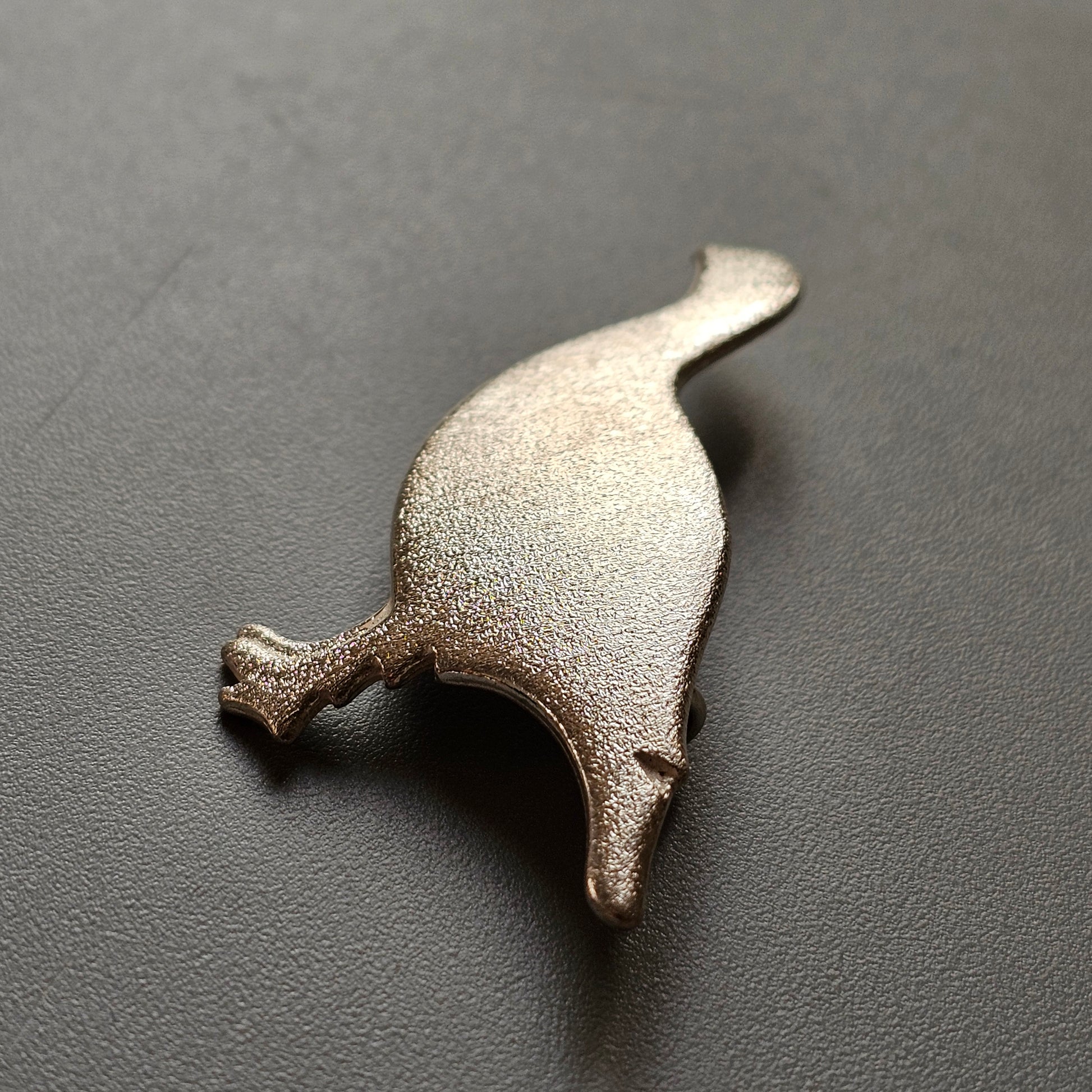 Metal bottle opener shaped like a stylized cat or feline figure.