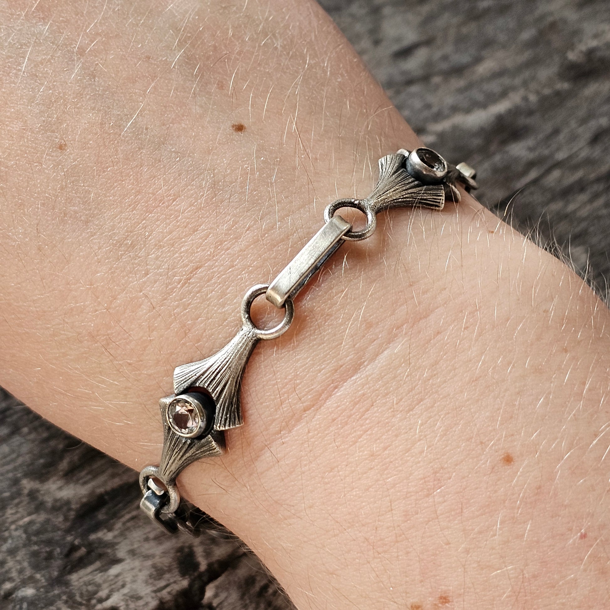 Silver bracelet with decorative floral or leaf-like charms.