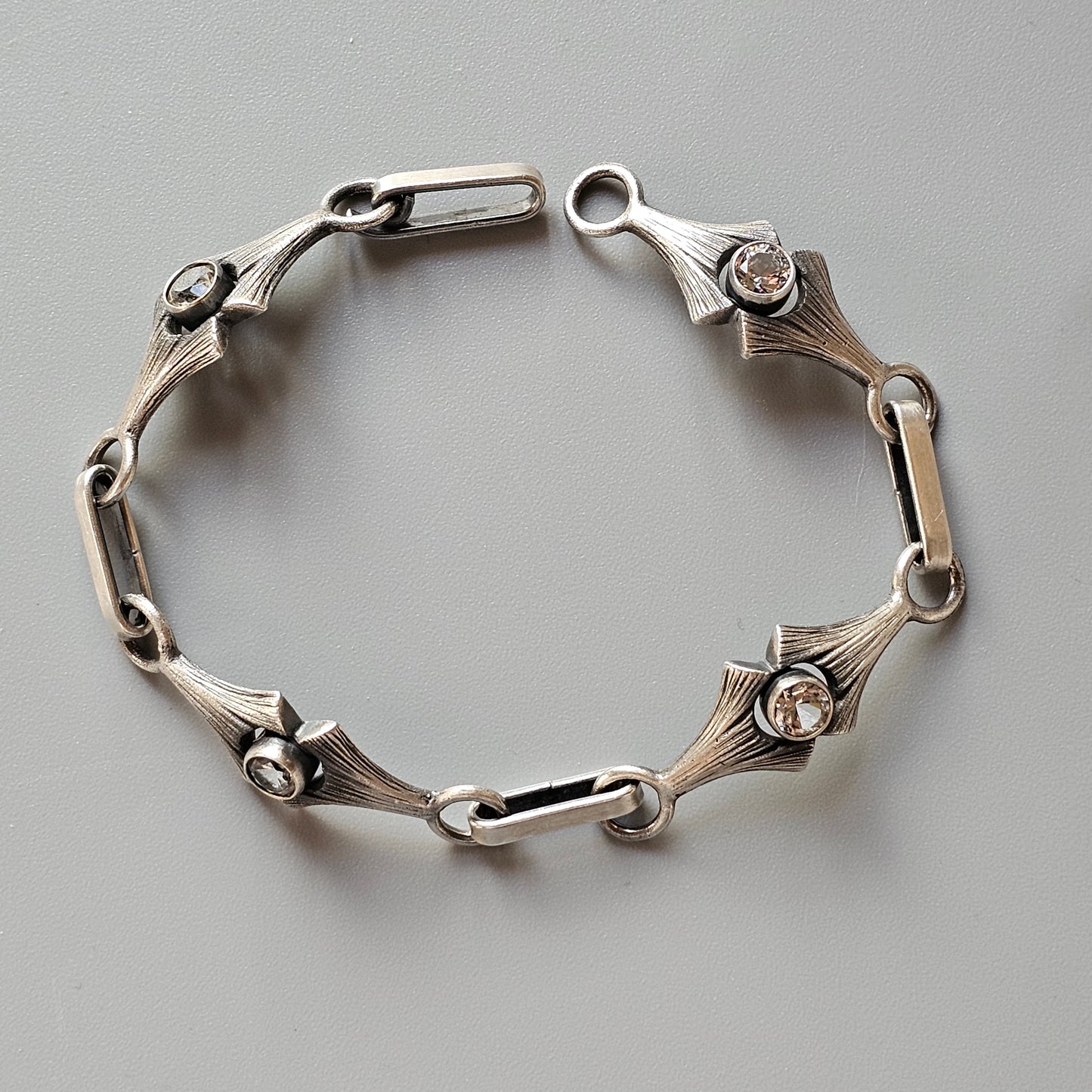 Silver bracelet with art deco-style links and small gemstones.