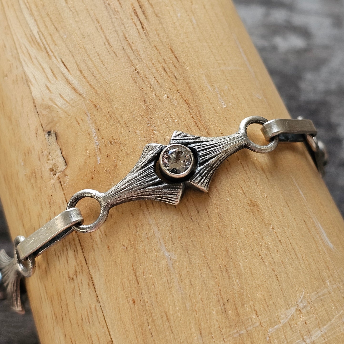 Silver bracelet with an Art Deco-inspired centerpiece featuring a small gemstone.